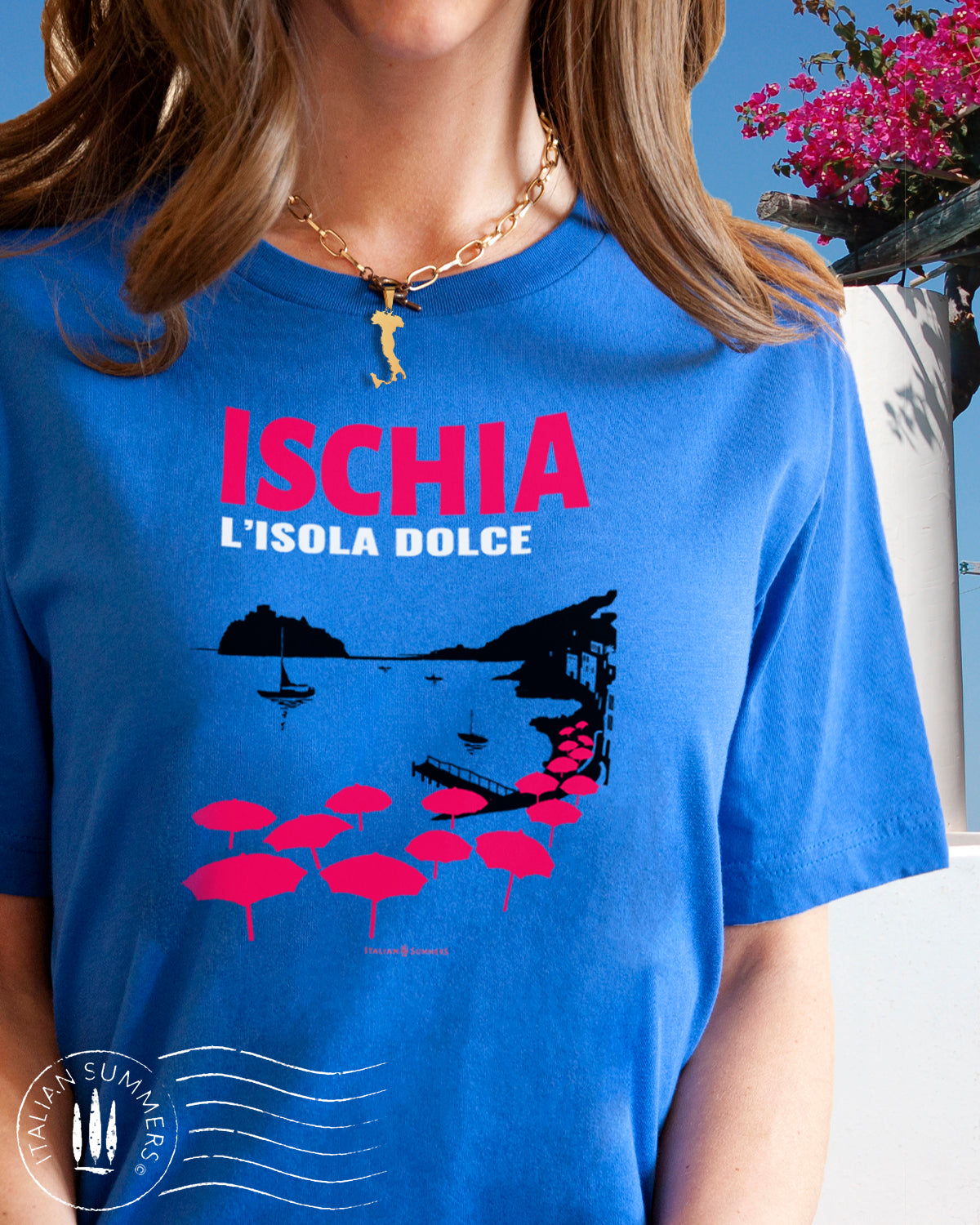 Italy Inspired garment dyed T Shirt with the text: ISCHIA L'isola dolce (Ischia, the sweet island)  with the print of the island's beach with the famous Aragonese Castle in the backround, with colored beach umbrellas strewn in the foreground. Made by Italian Summers