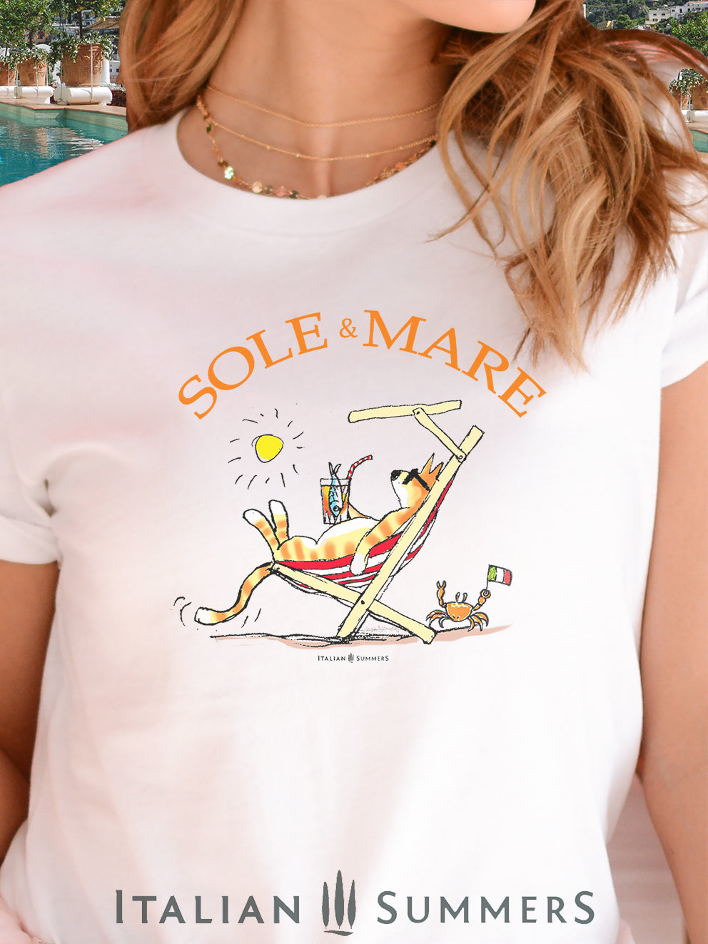 Italy inspired  White T Shirt our original drawing of a red cat on a beach chair sipping on a spritz and enjoying the sun in Italy. A cute crab on the sand waves a little Italian flag. Made by Italian Summers