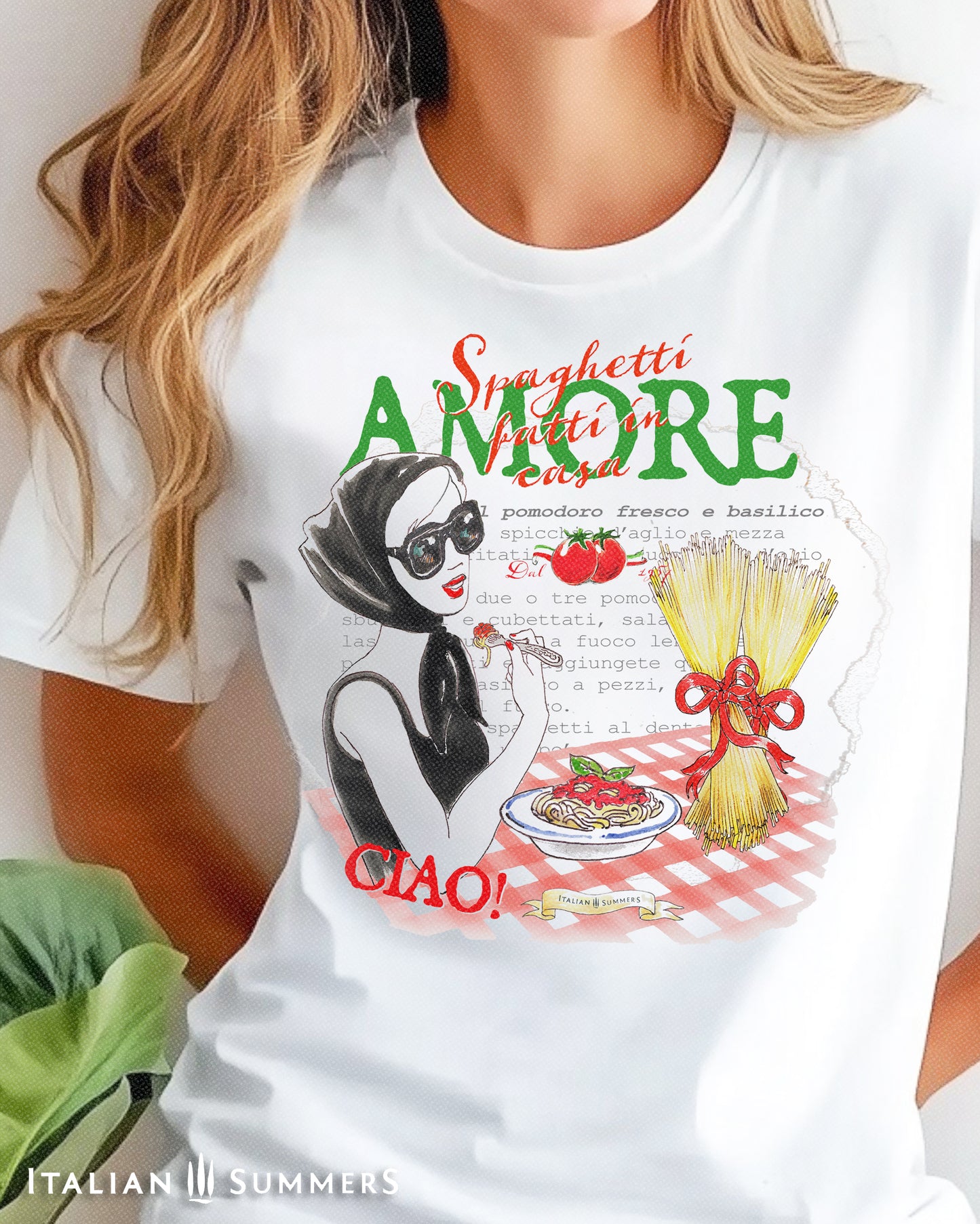 A woman wearing a white T shirt with drawing of a lady eating spaghetti while wearing a fashionable pair of glasses and the text " Spaghetti fatti in Casa- Amore" also features a recipe for 'spaghetti al pomodoro e basilico' text in the backround.