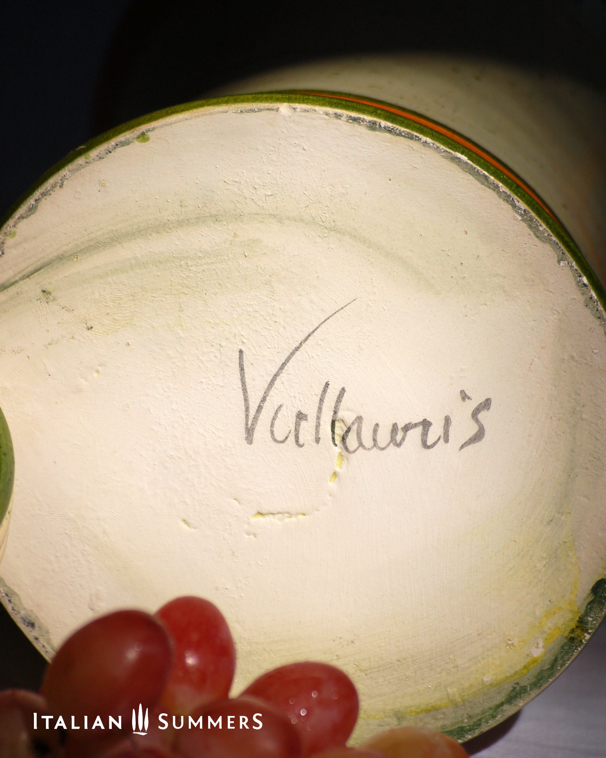 Close-up of a ceramic product with 'Vallauris' branding, with grapes in the foreground.