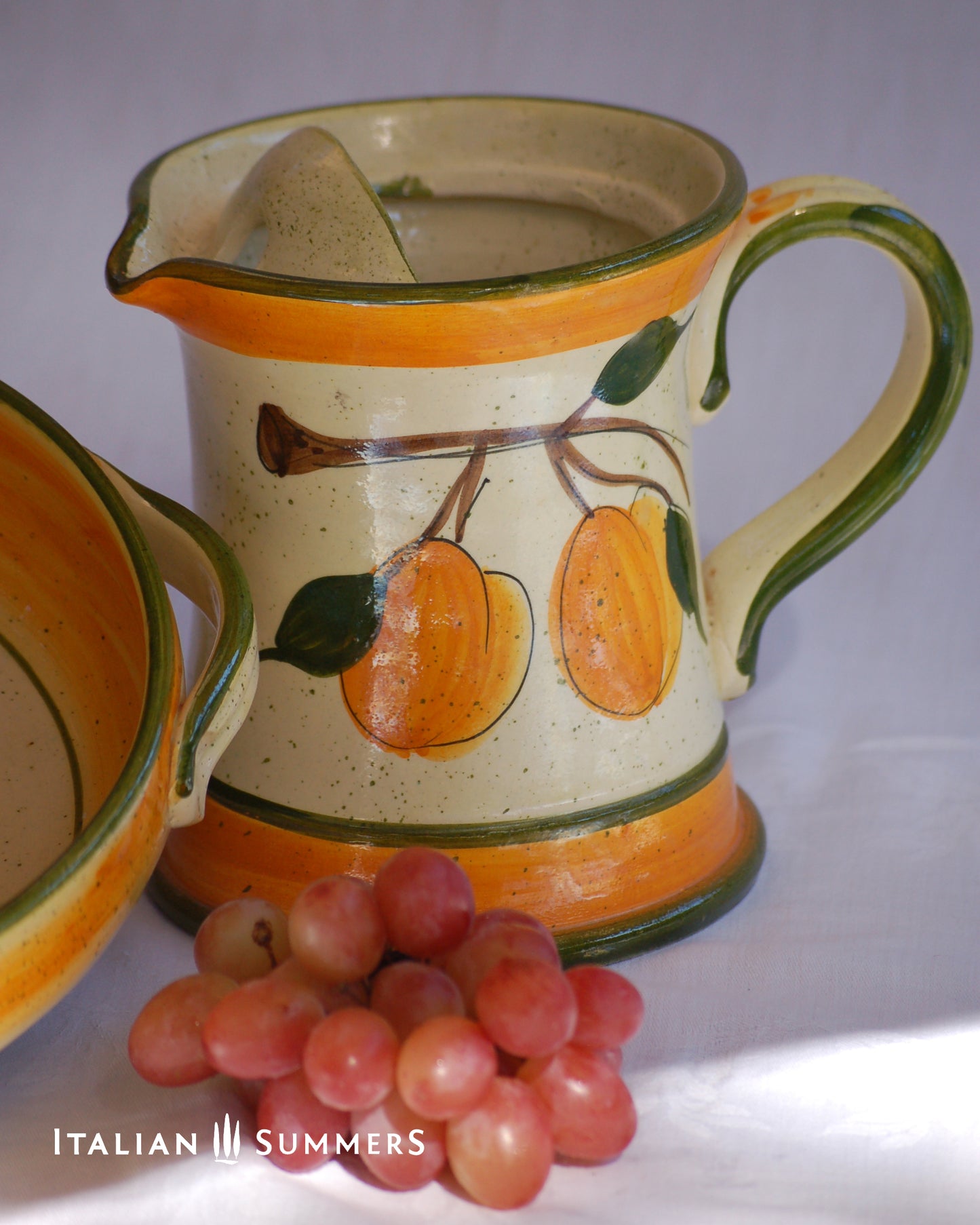 Ceramic pitcher with fruit design and grapes on a white background, featuring 'Italian Summers' branding.