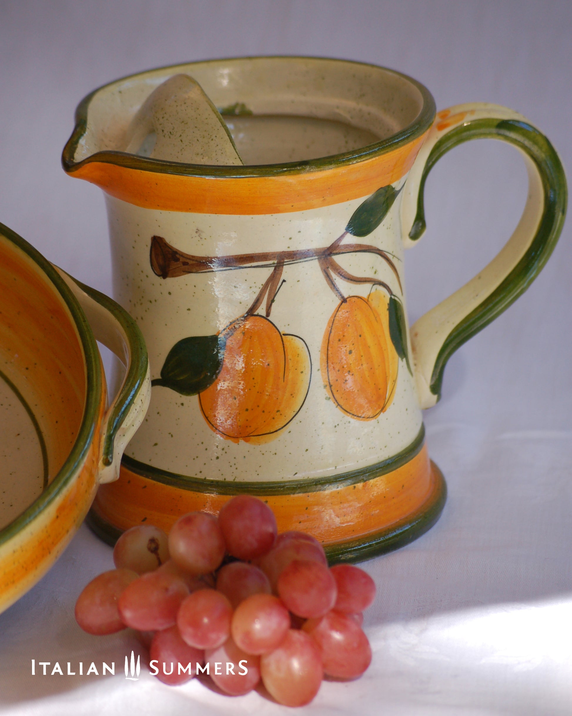 Ceramic pitcher with fruit design and grapes on a white background, featuring 'Italian Summers' branding.