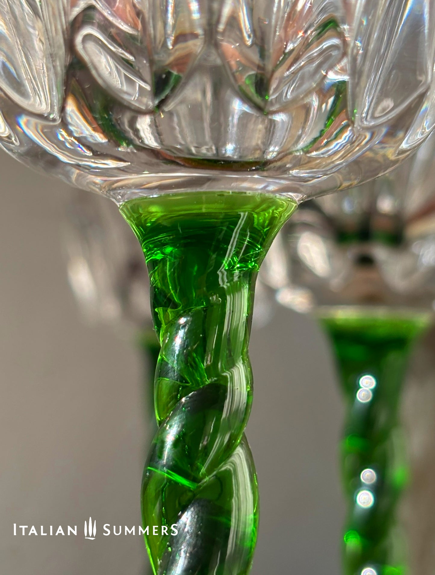 Close-up of a crystal wine glass with a  green spiral stem,  featuring 'Italian Summers' branding.