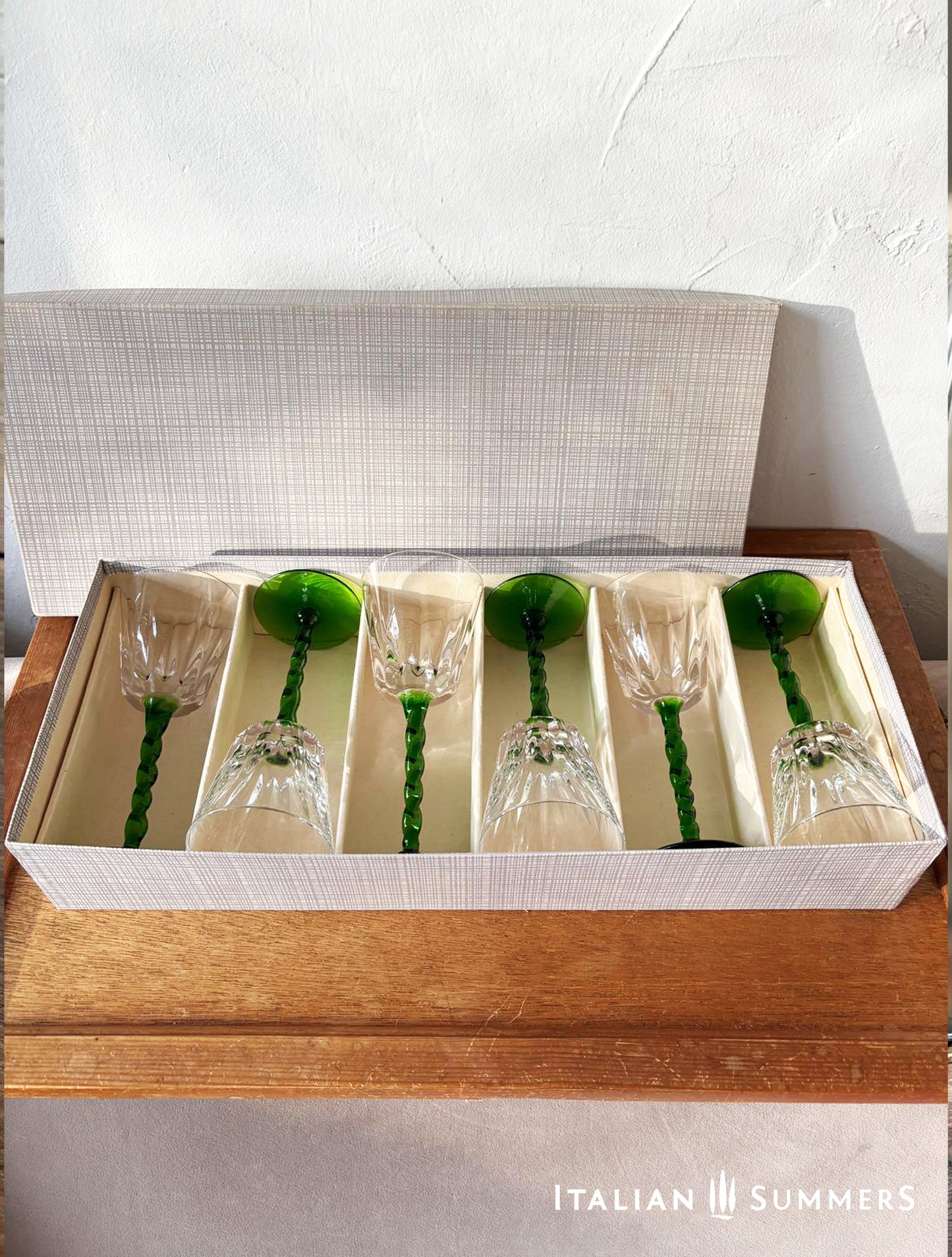 Set of six glass goblets with green stems in a box on a wooden surface, branded 'Italian Summers'.