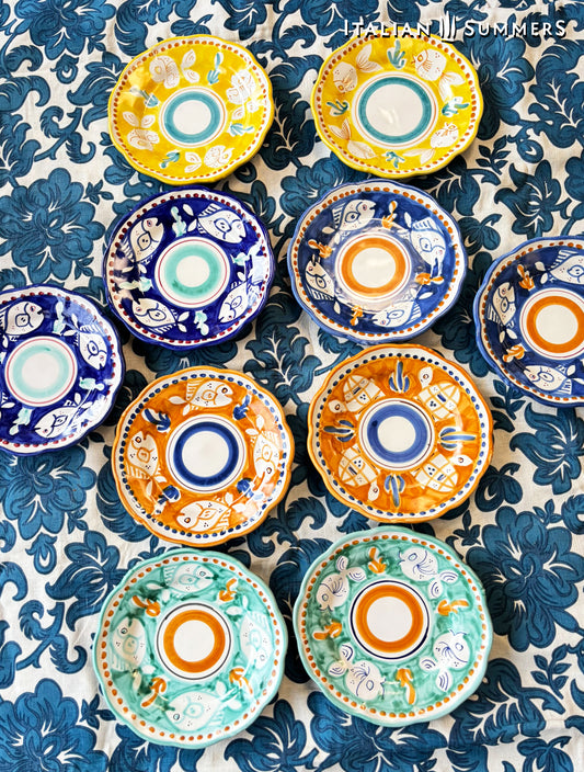  A lined-up group of Colorful hand-painted Vietri Pasta Plates with fish theme decorations from the Amalfi Coast on a blue and white tablecloth