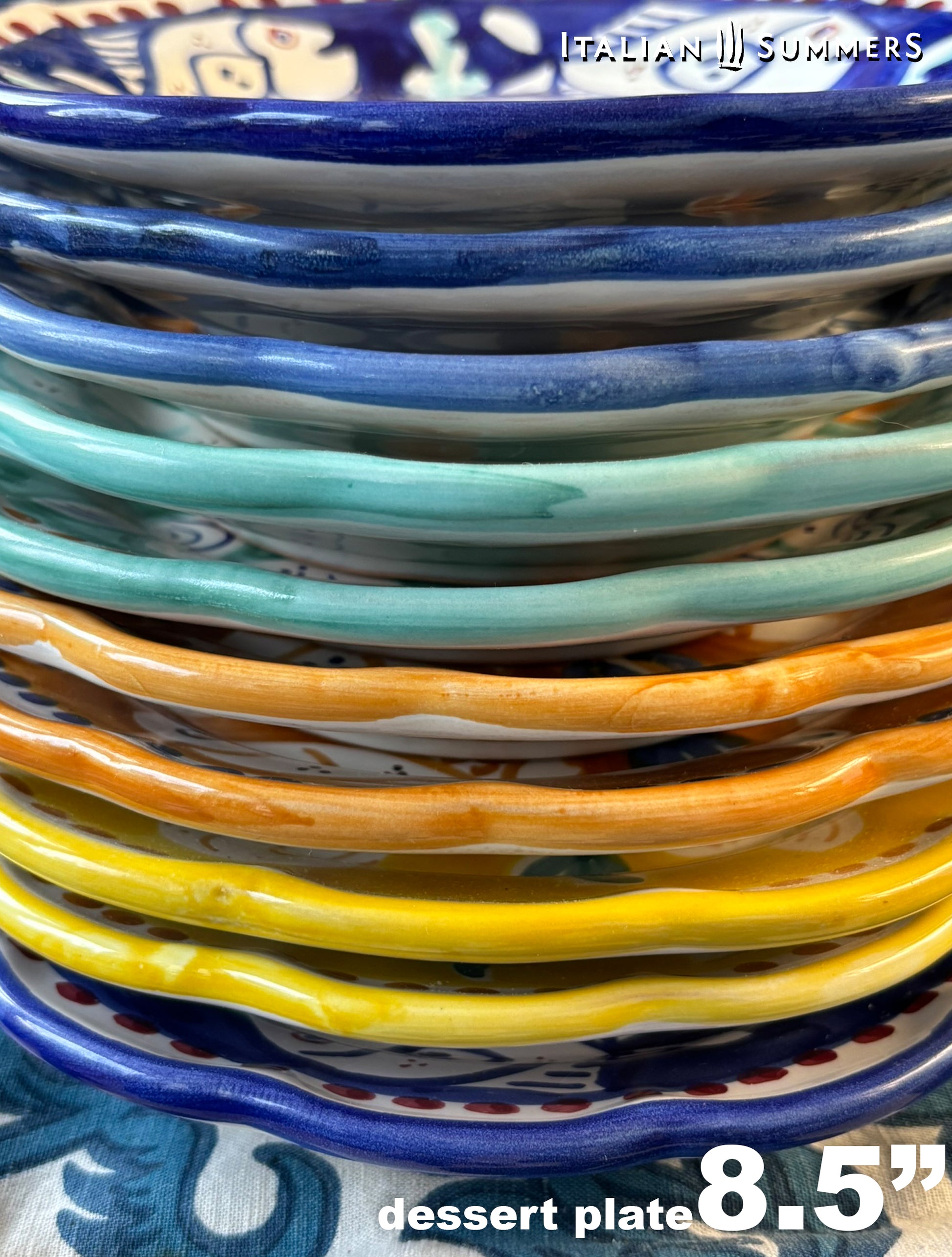 Close-up of a pile multi-Colored hand-painted Vietri Pasta Plates with fish theme decorations from the Amalfi Coast on a blue and white tablecloth