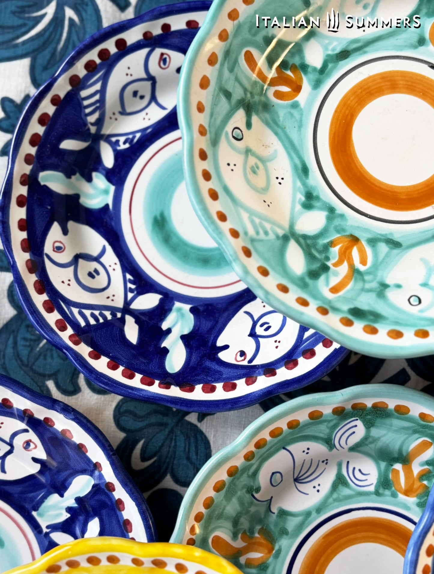  A group of multi-Colored hand-painted Vietri Pasta Plates with fish theme decorations from the Amalfi Coast on a blue and white tablecloth