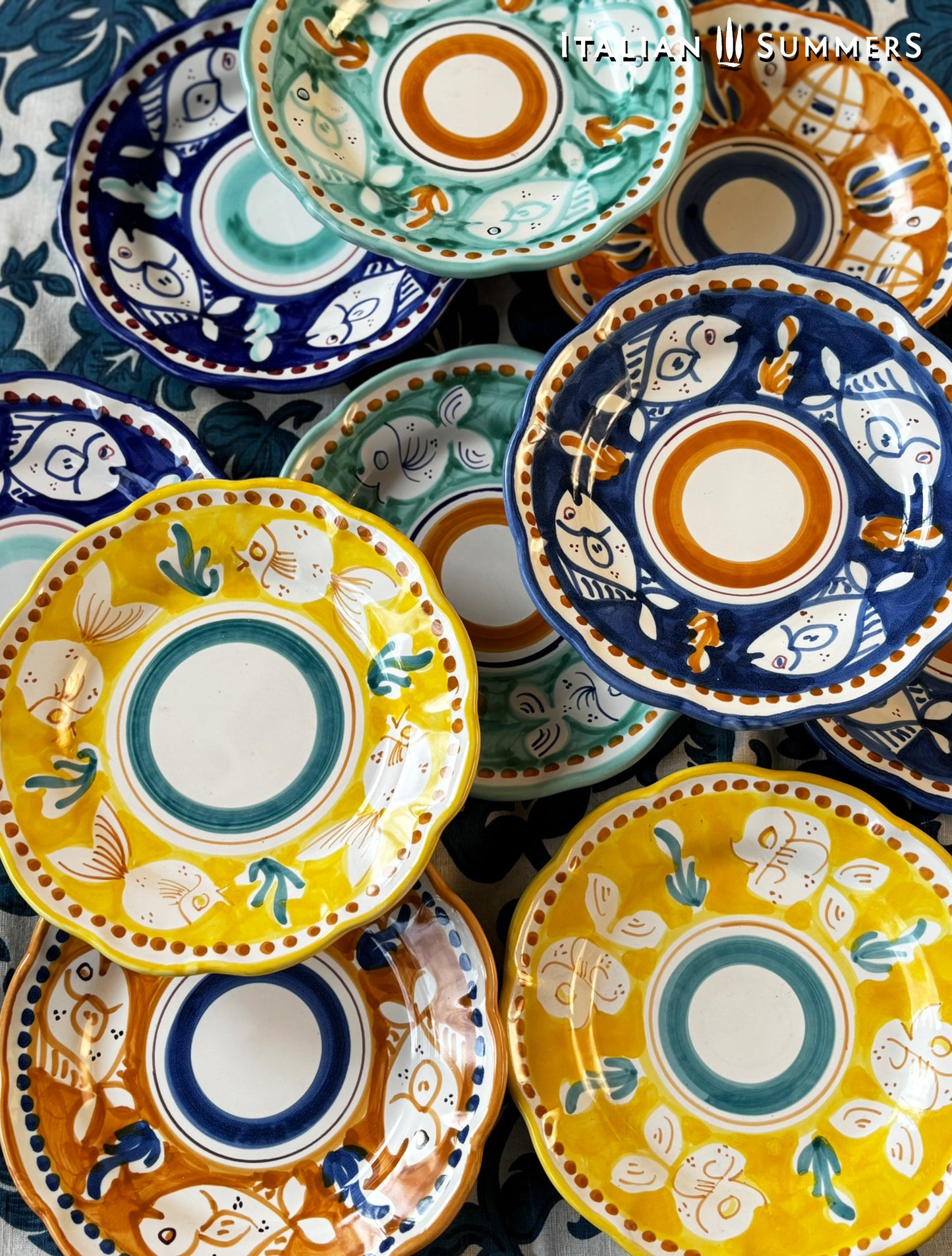  A large group of multi-Colored hand-painted Vietri Pasta Plates with fish theme decorations from the Amalfi Coast on a blue and white tablecloth