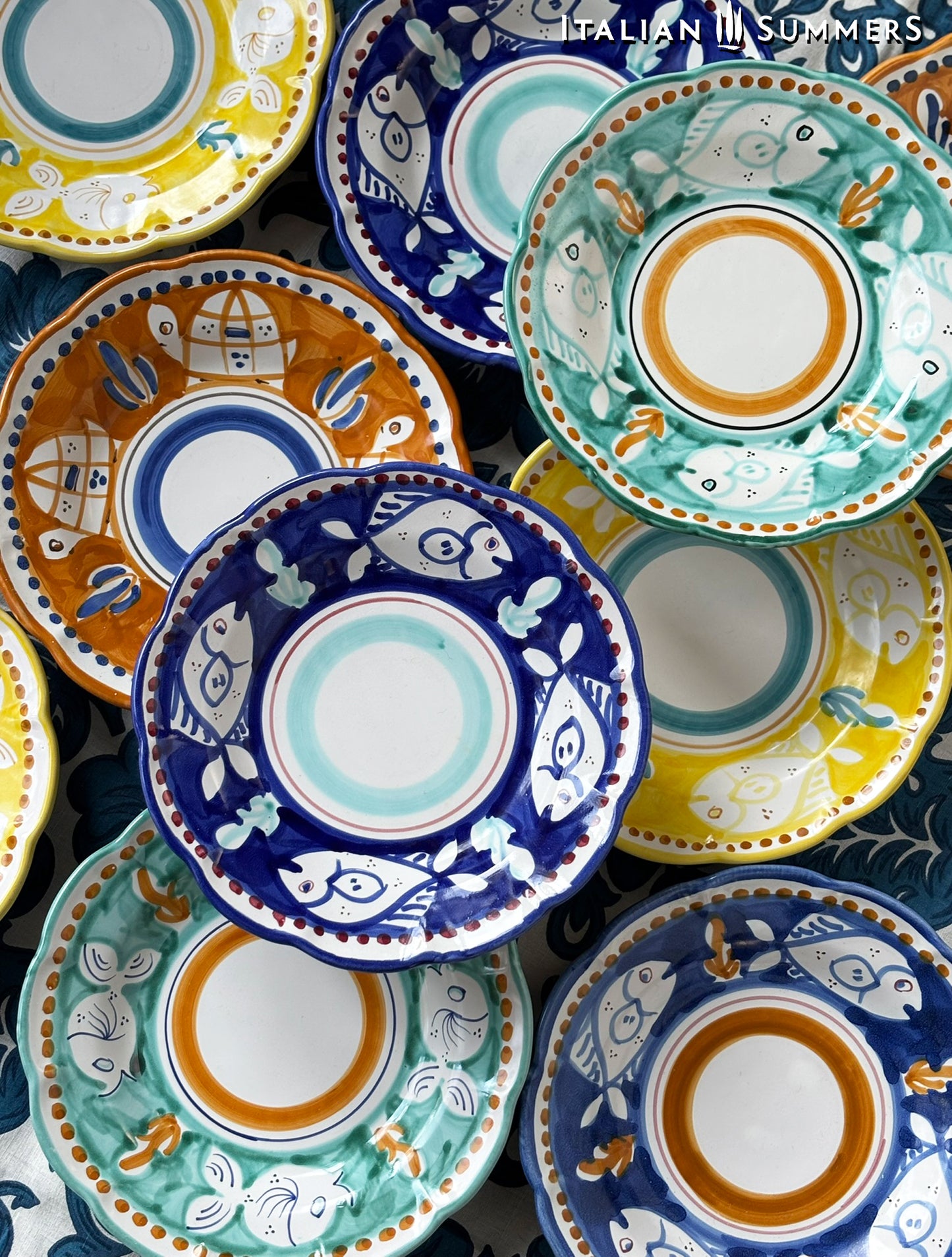 A group of Colorful hand-painted Vietri Plates from the Amalfi Coast o a blue and white tablecloth