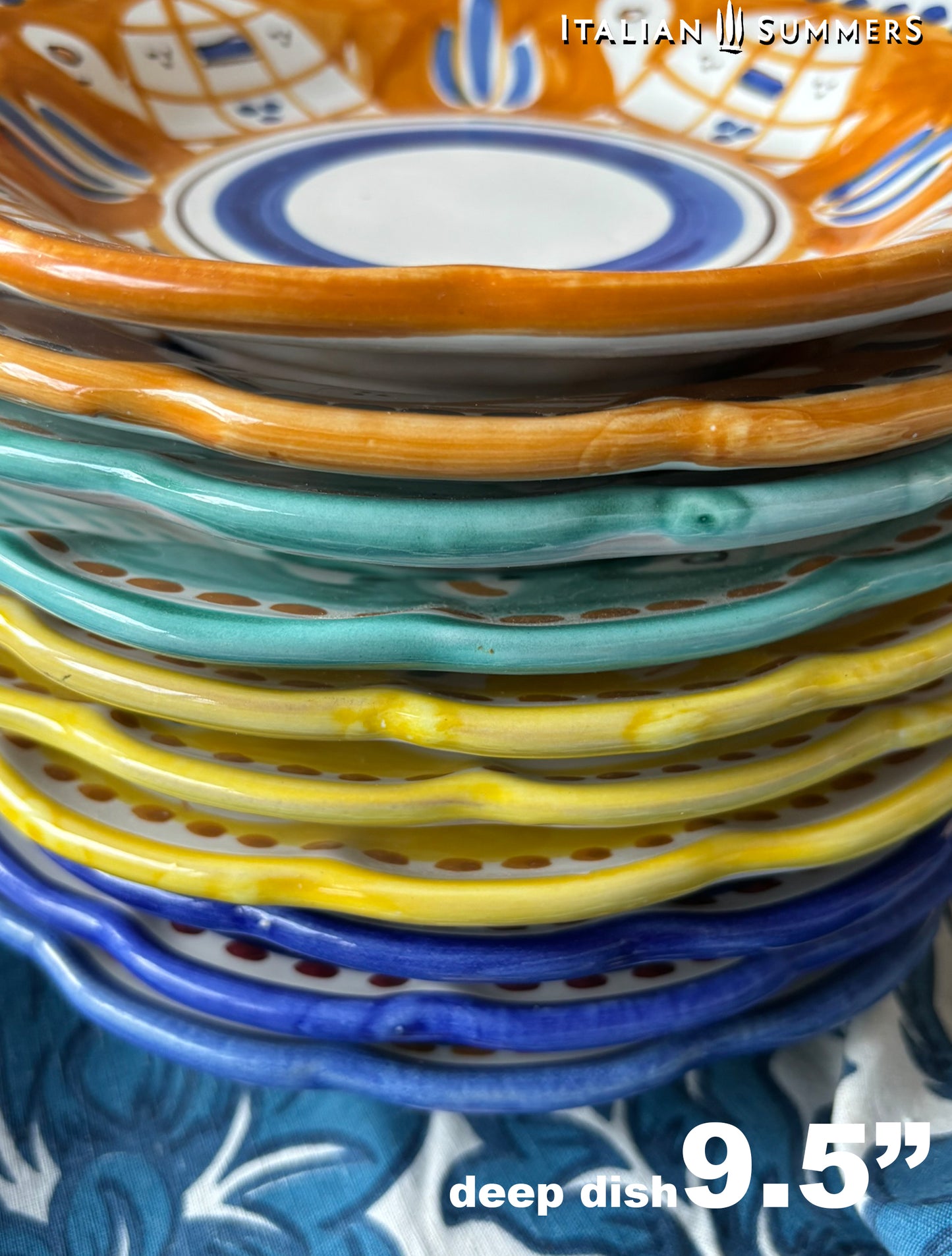  A detail of a pile of Colorful hand-painted Vietri Pasta Plates with fish theme decorations from the Amalfi Coast on a blue and white tablecloth