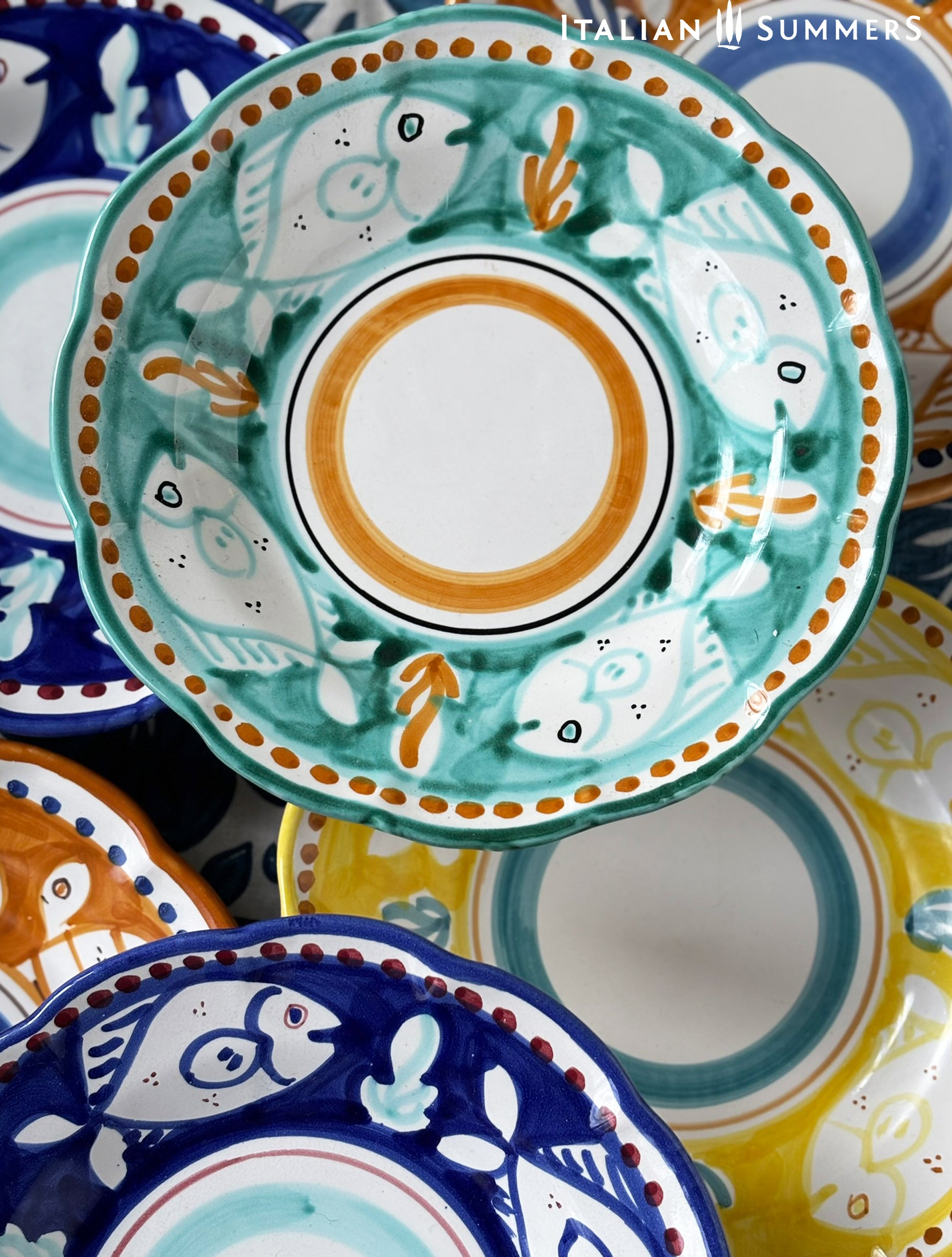 Detail of Aa group of Colorful hand-painted Vietri Plates from the Amalfi Coast o a blue and white tablecloth
