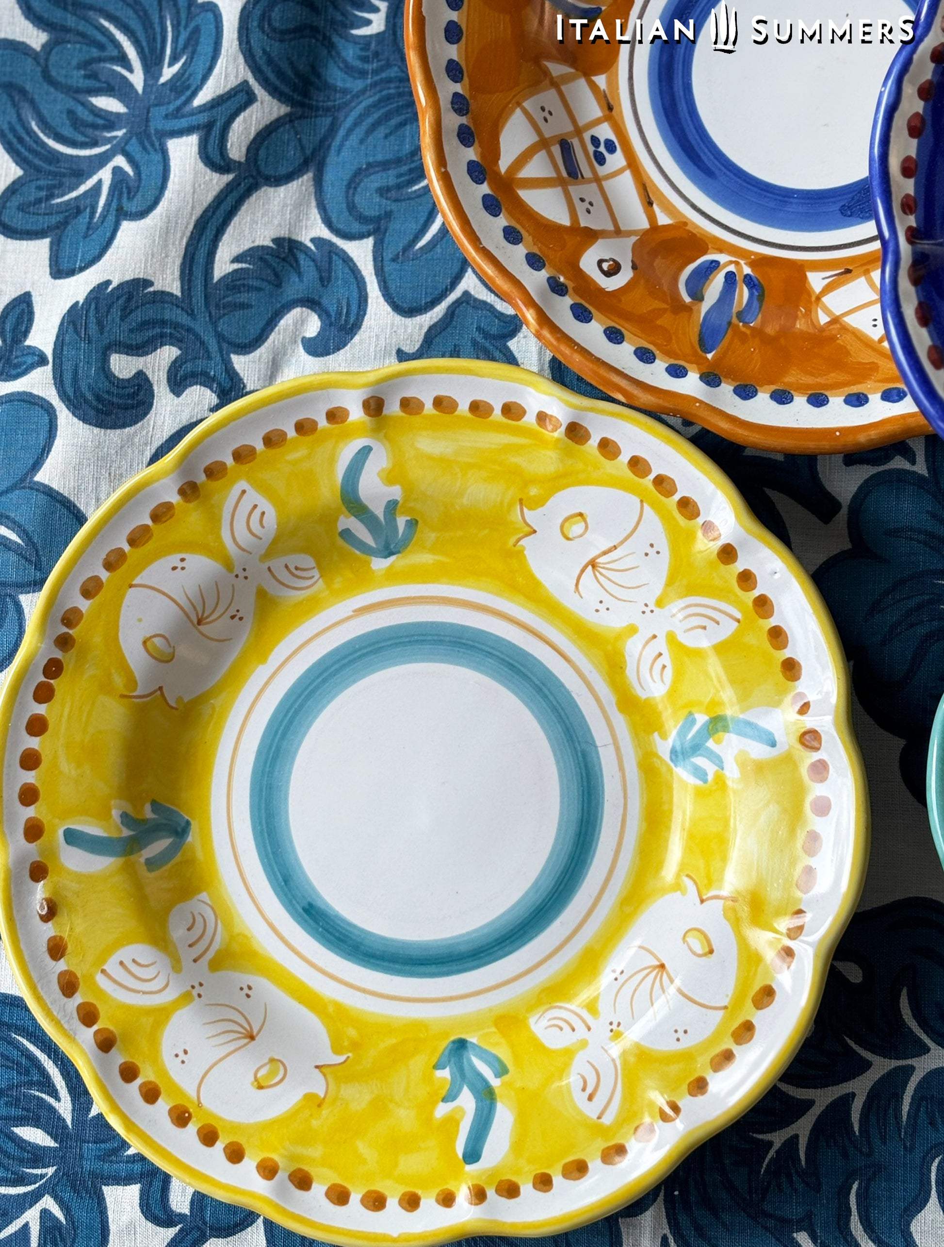 Two Colorful hand-painted Vietri Pasta Plates with fish theme decorations from the Amalfi Coast on a blue and white tablecloth