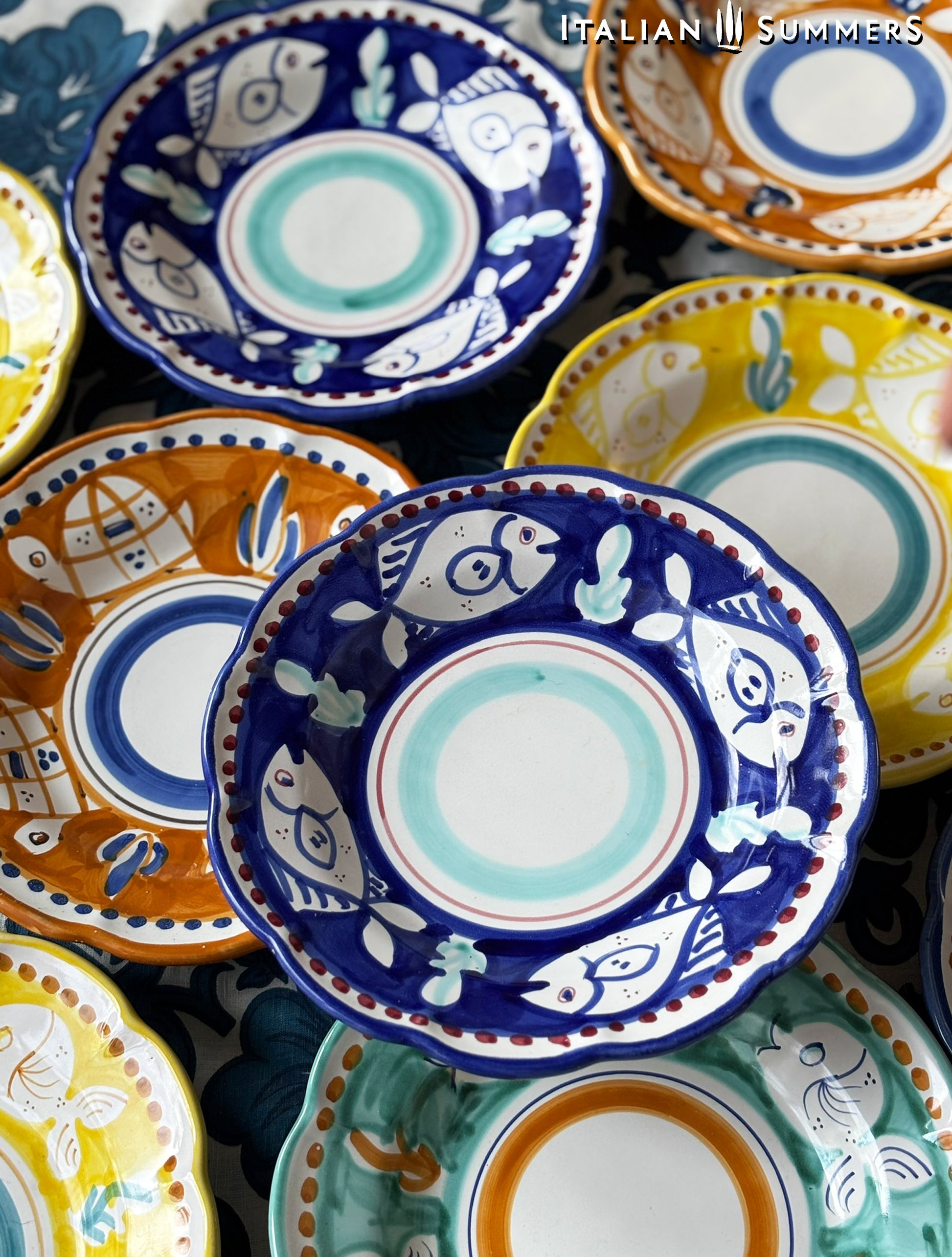  A group of Colorful hand-painted Vietri Pasta Plates with fish theme decorations from the Amalfi Coast on a blue and white tablecloth