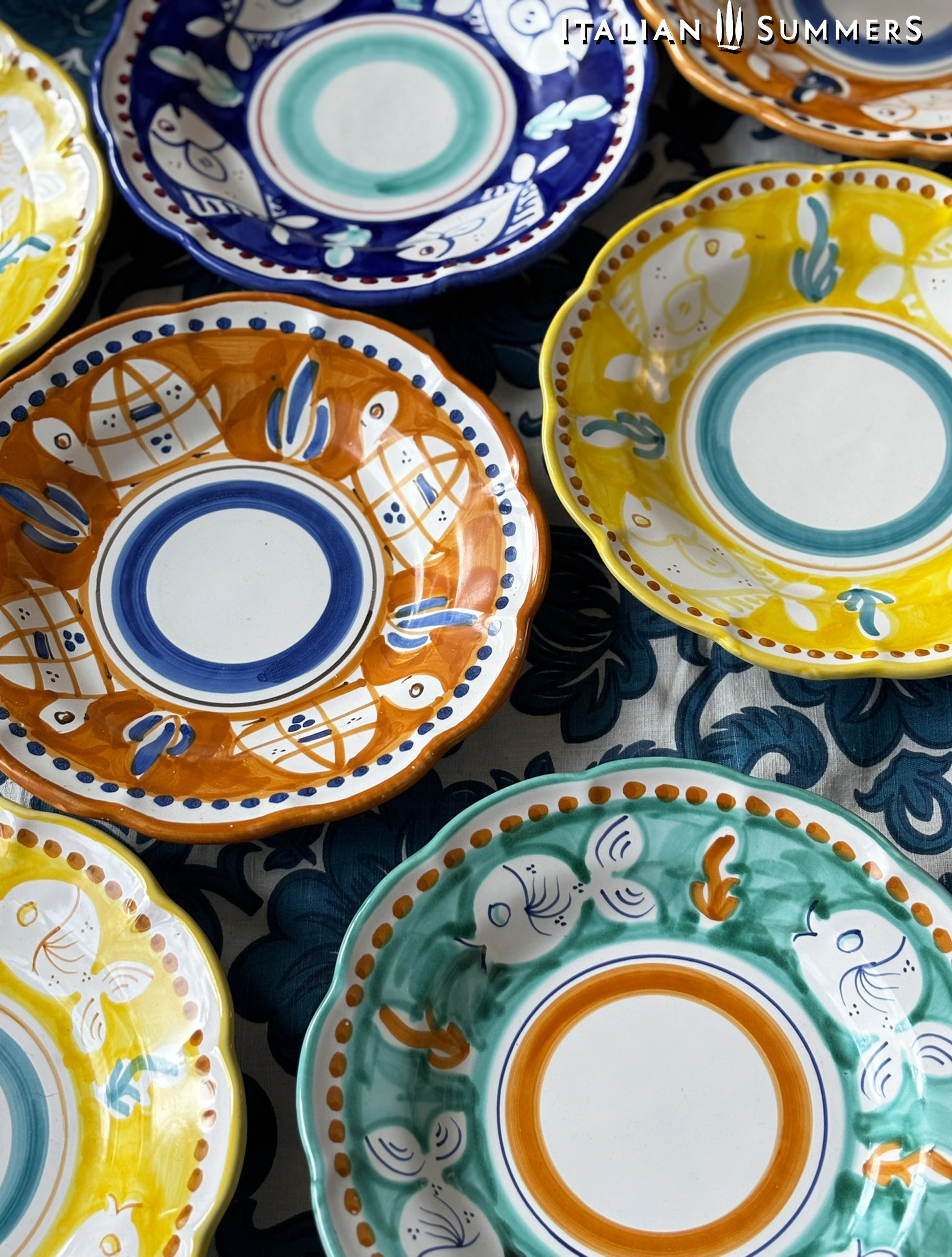  A group of Colorful hand-painted Vietri Pasta Plates with fish theme decorations from the Amalfi Coast on a blue and white tablecloth