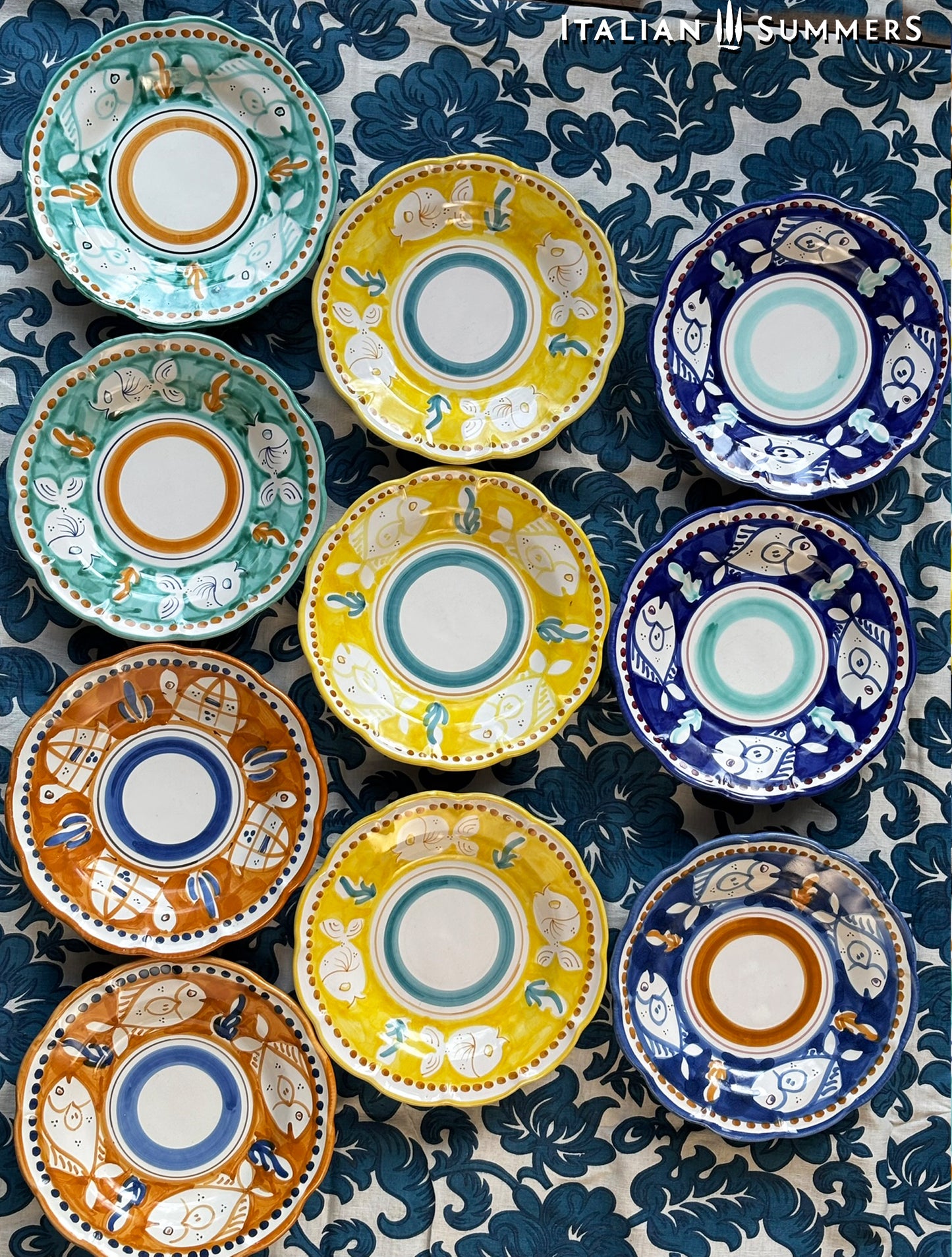  A lined up group of Colorful hand-painted Vietri Pasta Plates with fish theme decorations from the Amalfi Coast on a blue and white tablecloth