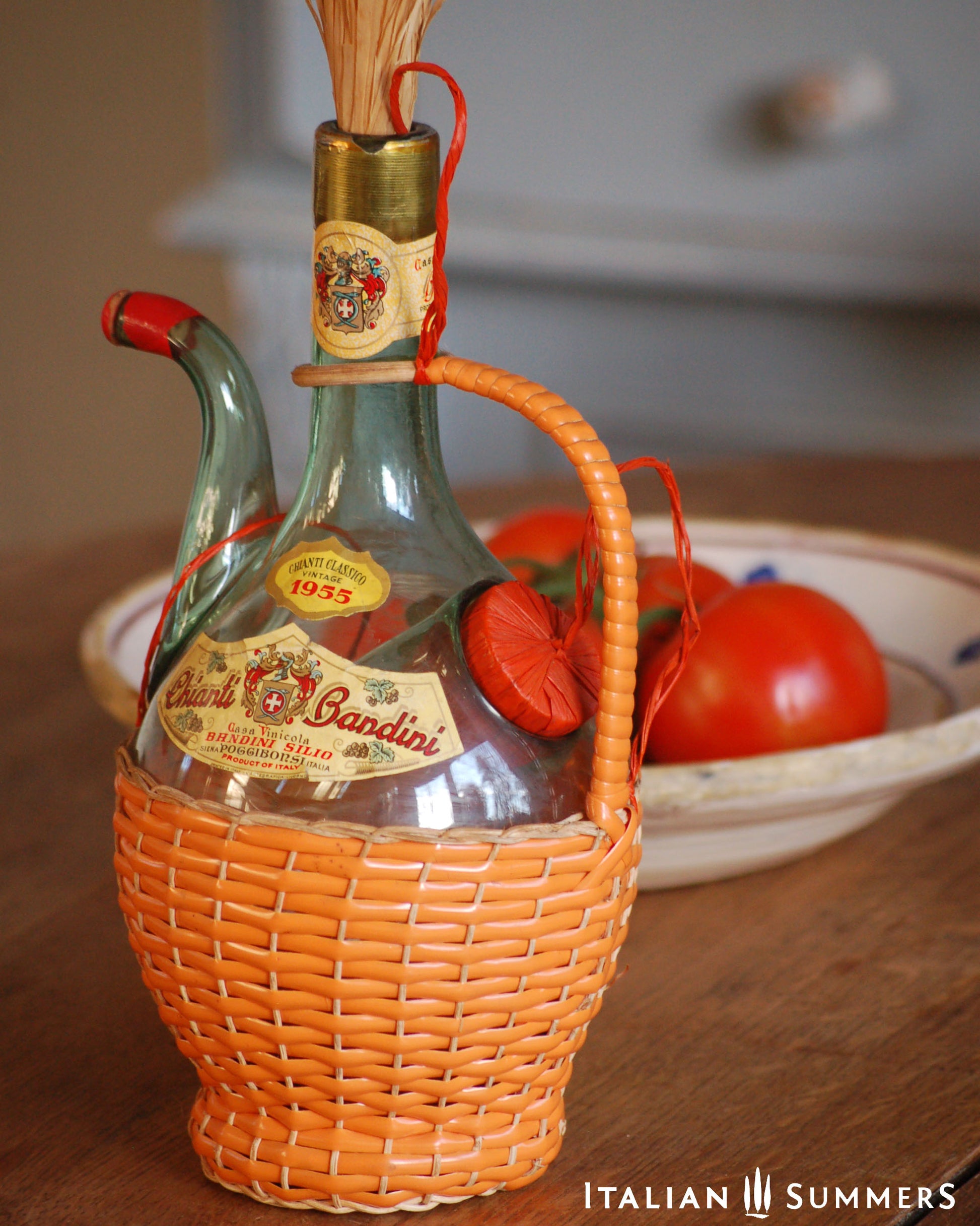 Vintage bottle of Chianti Wine  in an orange wicker basket with tomatoes in the background.