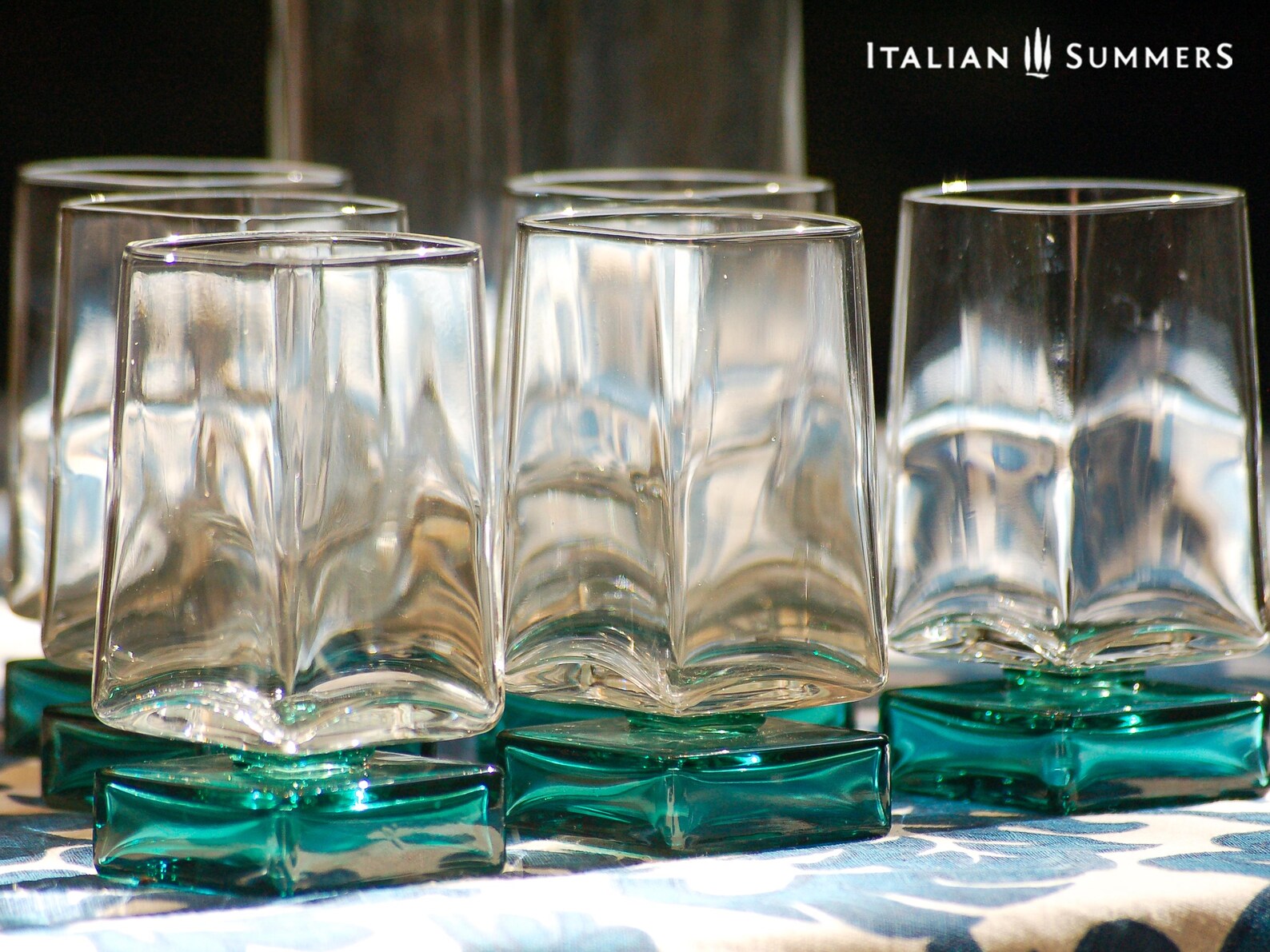 Vintage Bormioli Monet glass set from Italy, featuring square whiskey glasses with bold green foot and matching decanter, displayed on a table in retro style.