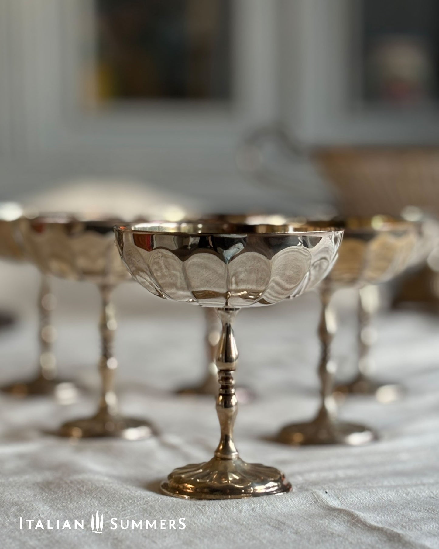 Silver pedestal bowls with intricate designs on a textured surface, branded 'Italian Summers'.