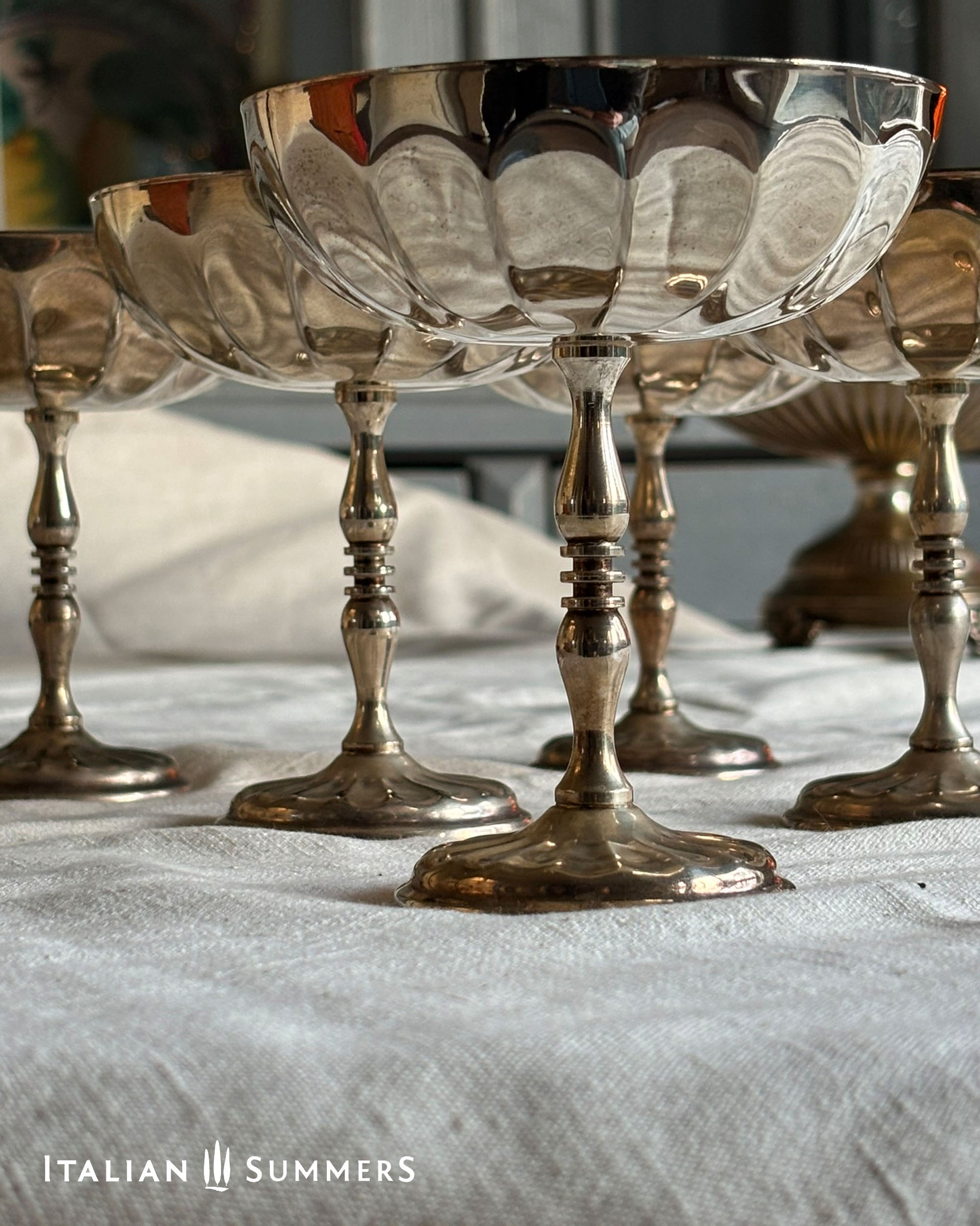 Silver goblets on a white cloth with 'Italian Summers' branding.