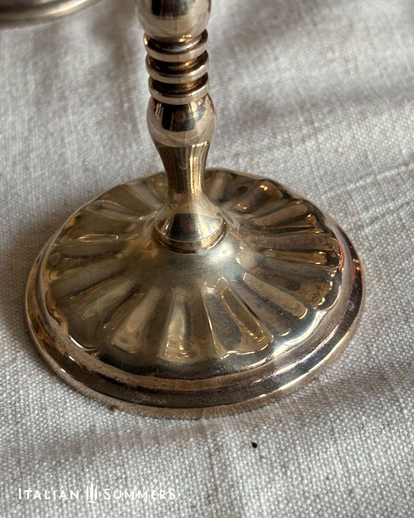 Close-up of a silver plated stemmed champagne coupe on a textured fabric background