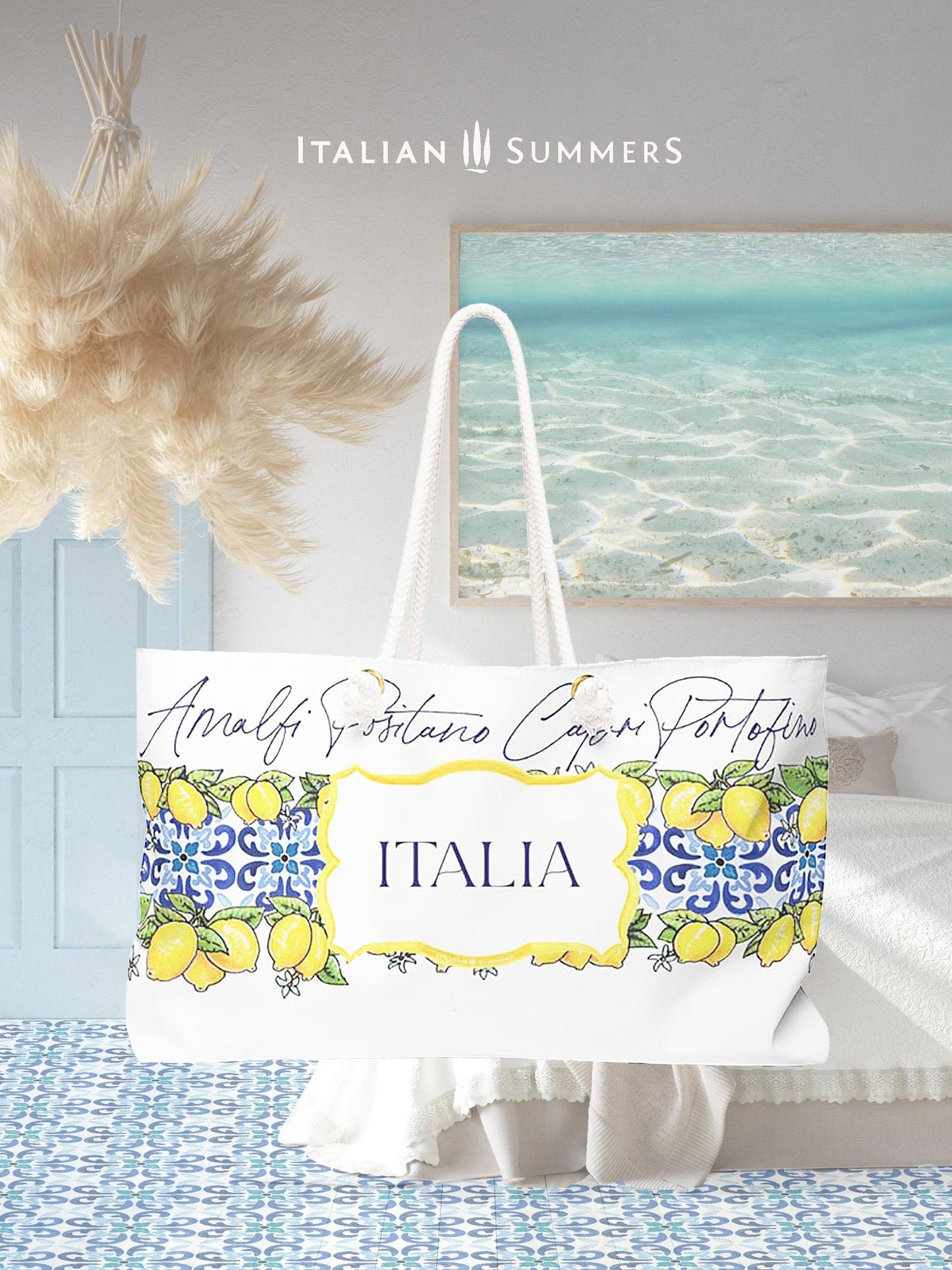 Italy-inspired XL Beach Bag  with printed blue Italian tiles in a  large band across the entire bag , framed with garlands of sunny, leafy Sorrento Lemons  with flowers. A large cartouche -like crest in the middle has the word  ITALIA - Seaside location names are writthen in flowing hand-script in blue across the top of the design. Sorrento, Positano, Ravello, Praiano, Capri, Amalfi, Procida,  made by Italian Summers