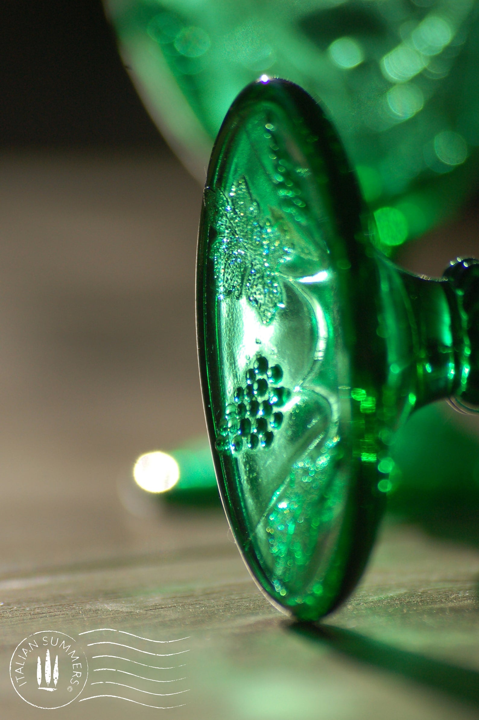 A rich emerald-green glass  set of six detail of the foot of a wine goblet with embossed grapes and vines motif from Tuscany.