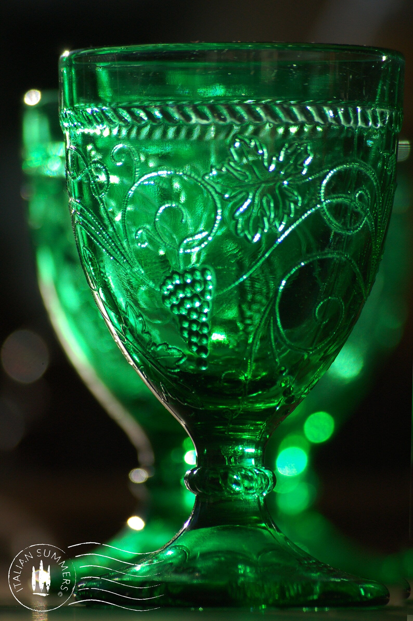 Green glass goblet with intricate patterns on a dark background