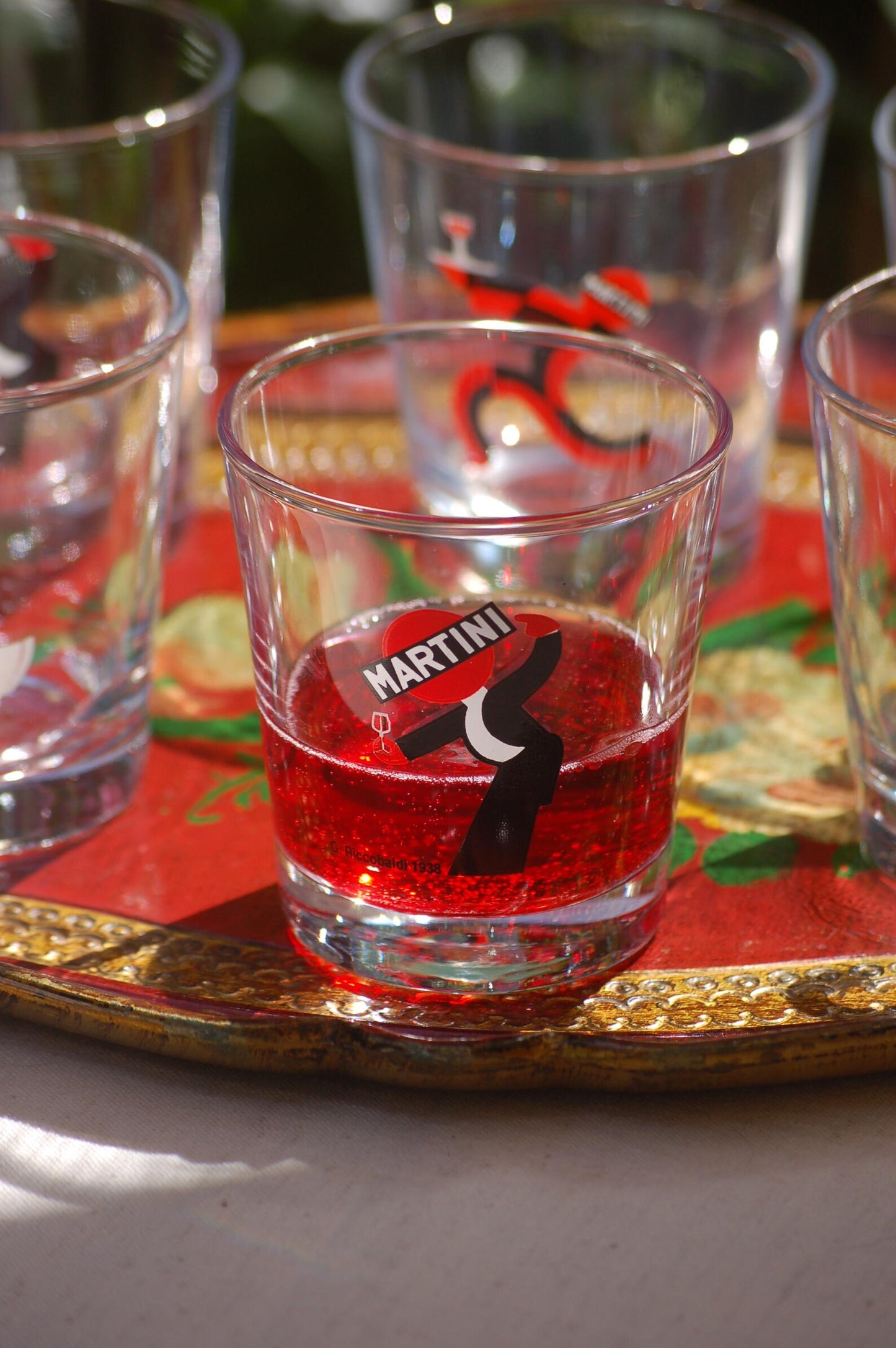 Clear glass with red liquid and Martini logo on a decorative tray