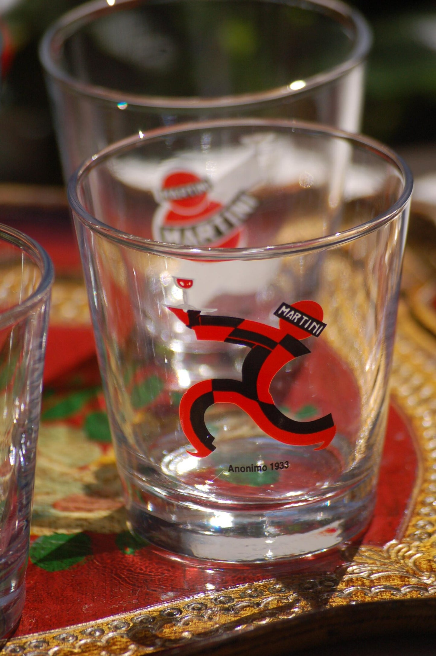 Clear Martini brand glass with a red and black logo on a decorative tray
