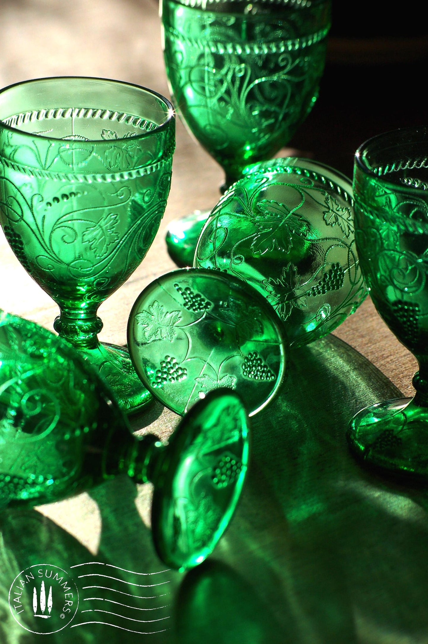 Set of green embossed glass goblets on a wooden surface