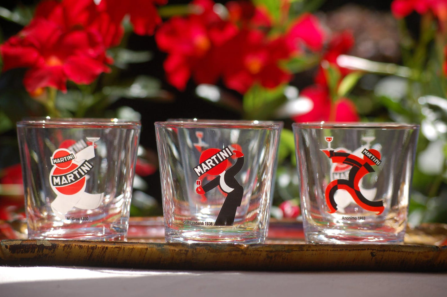 Three Martini-themed  glasses on a wooden tray with flowers in the background.
