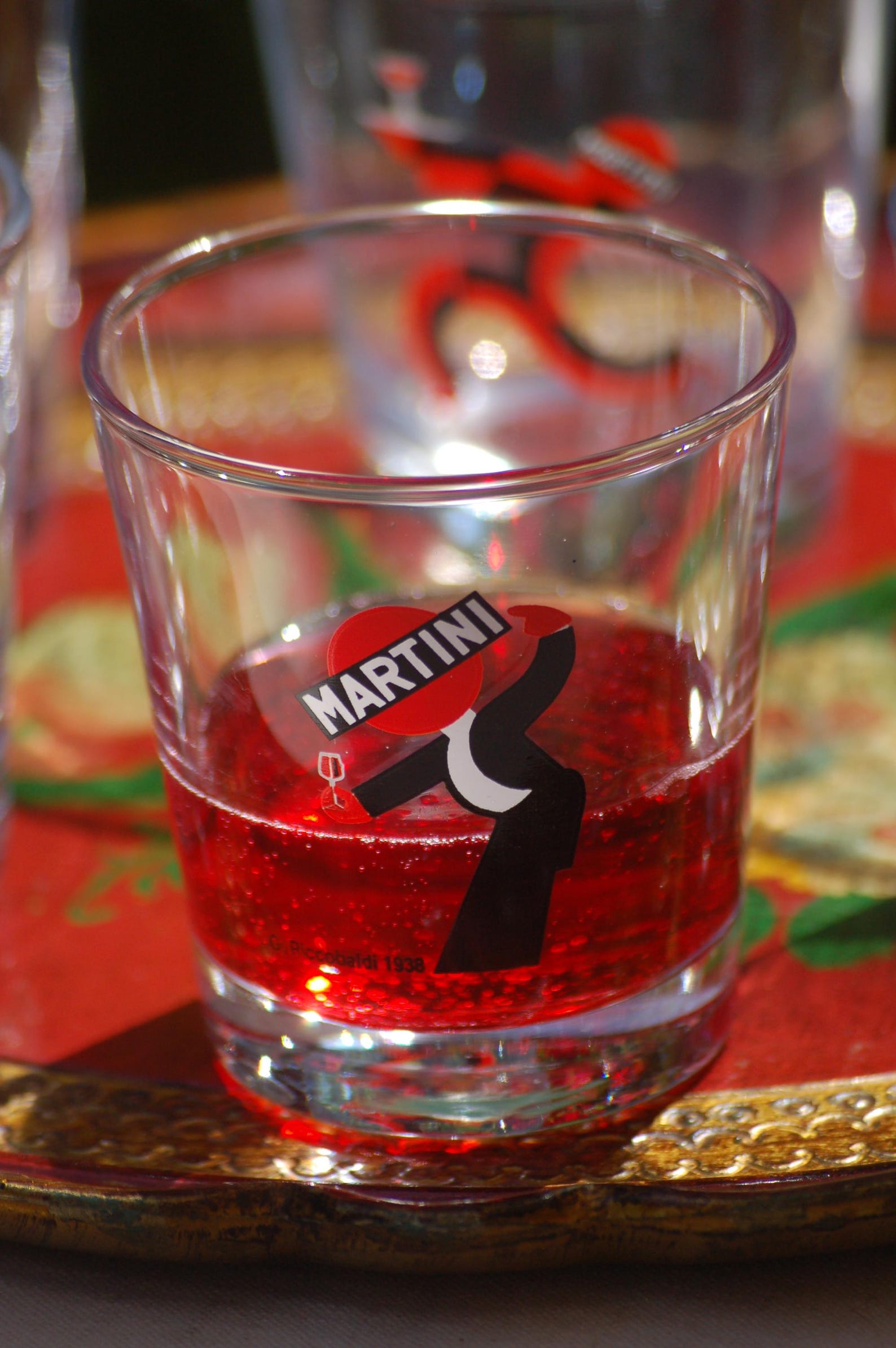 Clear glass with red liquid and Martini logo on a blurred background