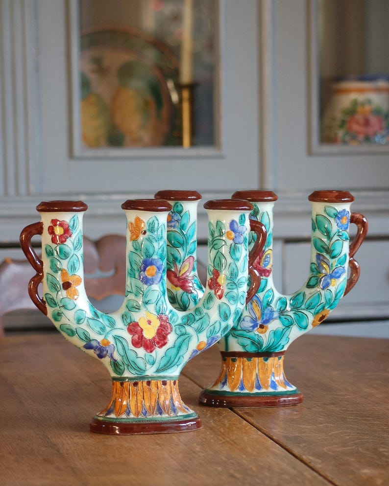 Colorful pair of  ceramic candleholders by Cerart Monaco  with floral design on a wooden surface