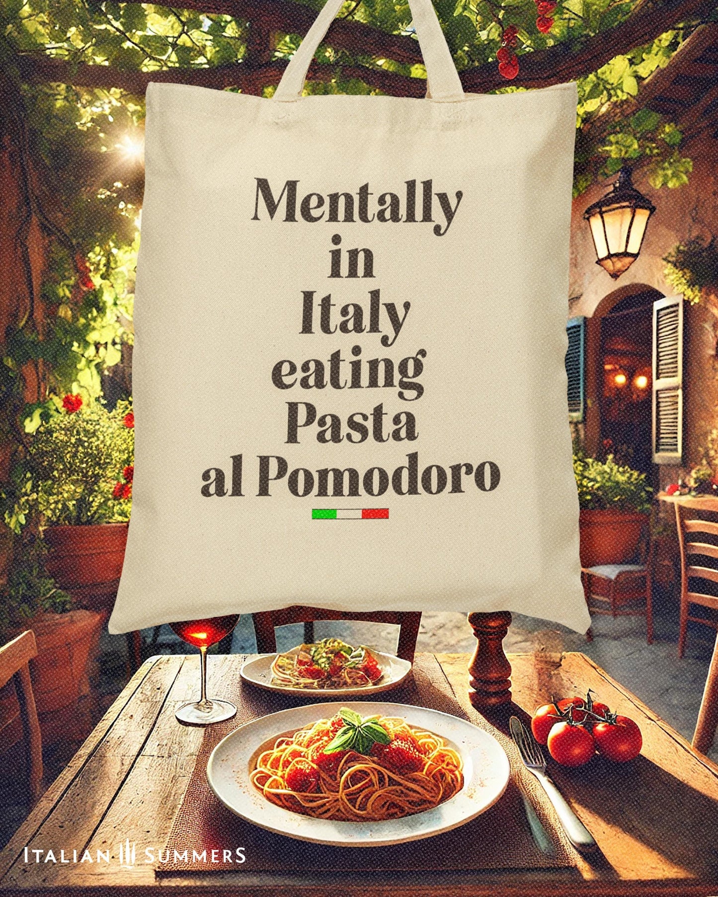 Italy canvas tote bag with the text Mentally in Italy eating Pasta al Pomodoro. Under the text you see a little bar with the happy colors of the Italian flag. The text of the quote is in black. Designed by Italian Summers