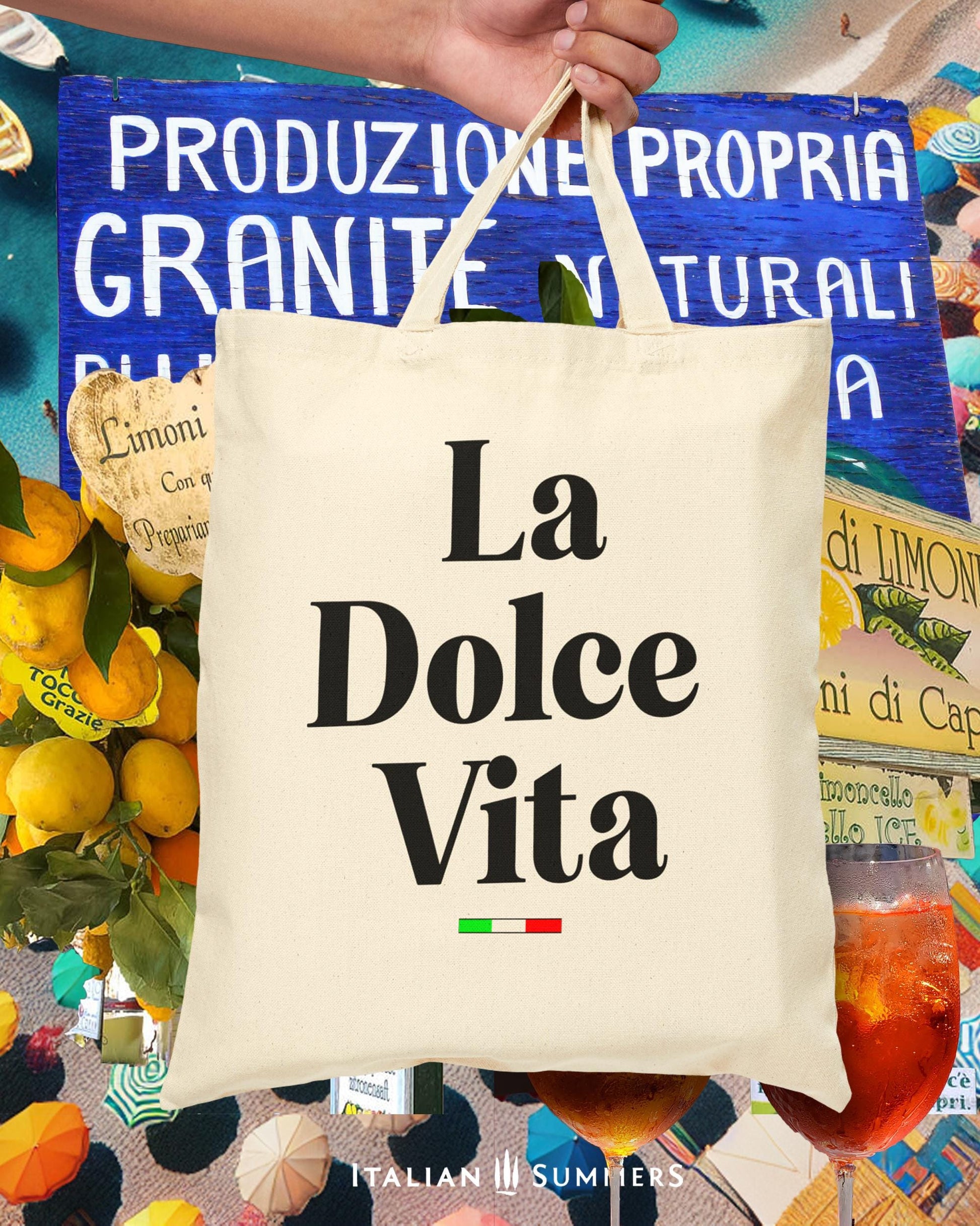 A cotton canvas tote bag with the text La Dolce Vita  floats in front of colorful and Idyllic collage  of Amalfi  Coast Lemons, granite vendor signs, Aperol Spritz glasses.