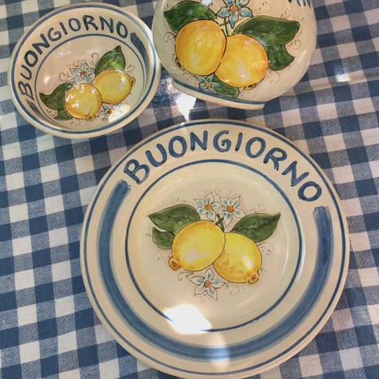 Ceramic plate Buongiorno Limoni handpainted in Sicily. This  plate has the quote Biongiorno on the rim - handpainted  - And colorfull lemons on the center of the plate  with lemon flowers. On the rim of the plate there are blue paint stripes. The blue color is ultra marine. This plate is designed and sold by Italian Summers.