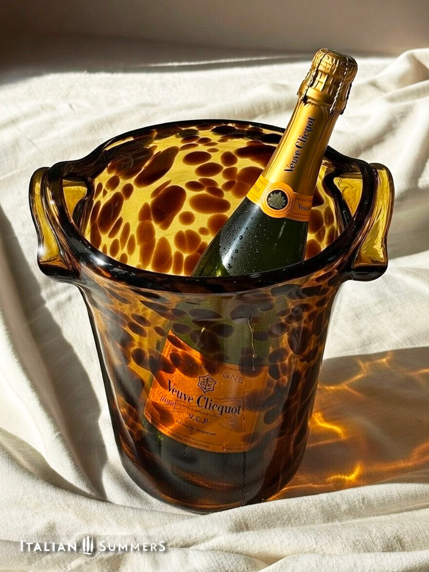 a bottle of champagne in a tortoise shell glass  ice bucket on a white surface.