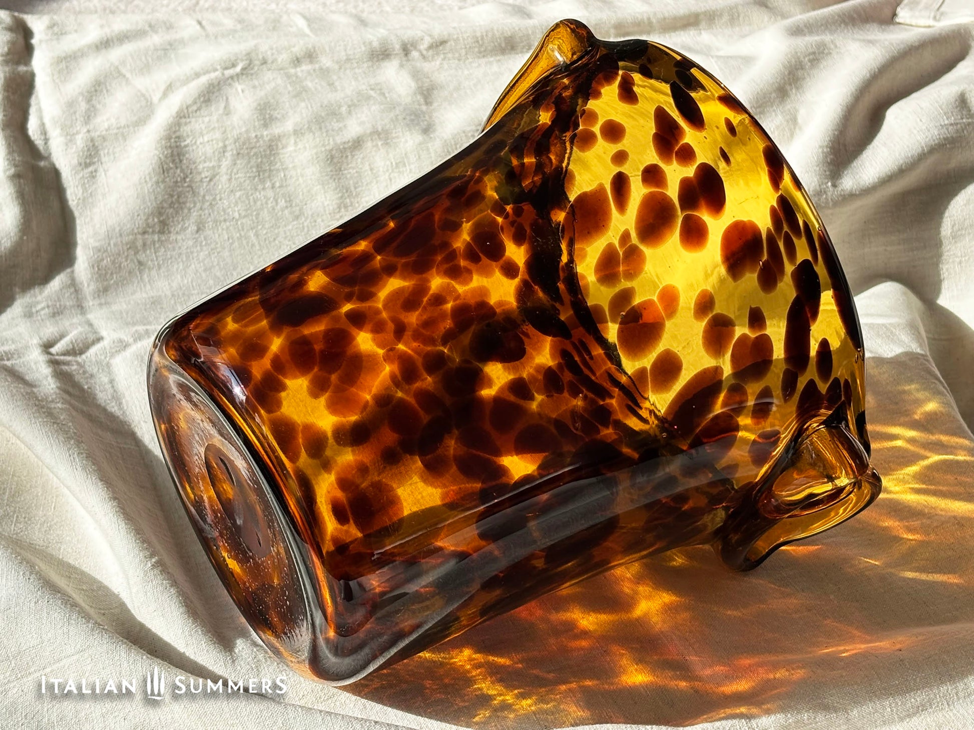 Tortoiseshell patterned glass ice bucket on a light fabric background