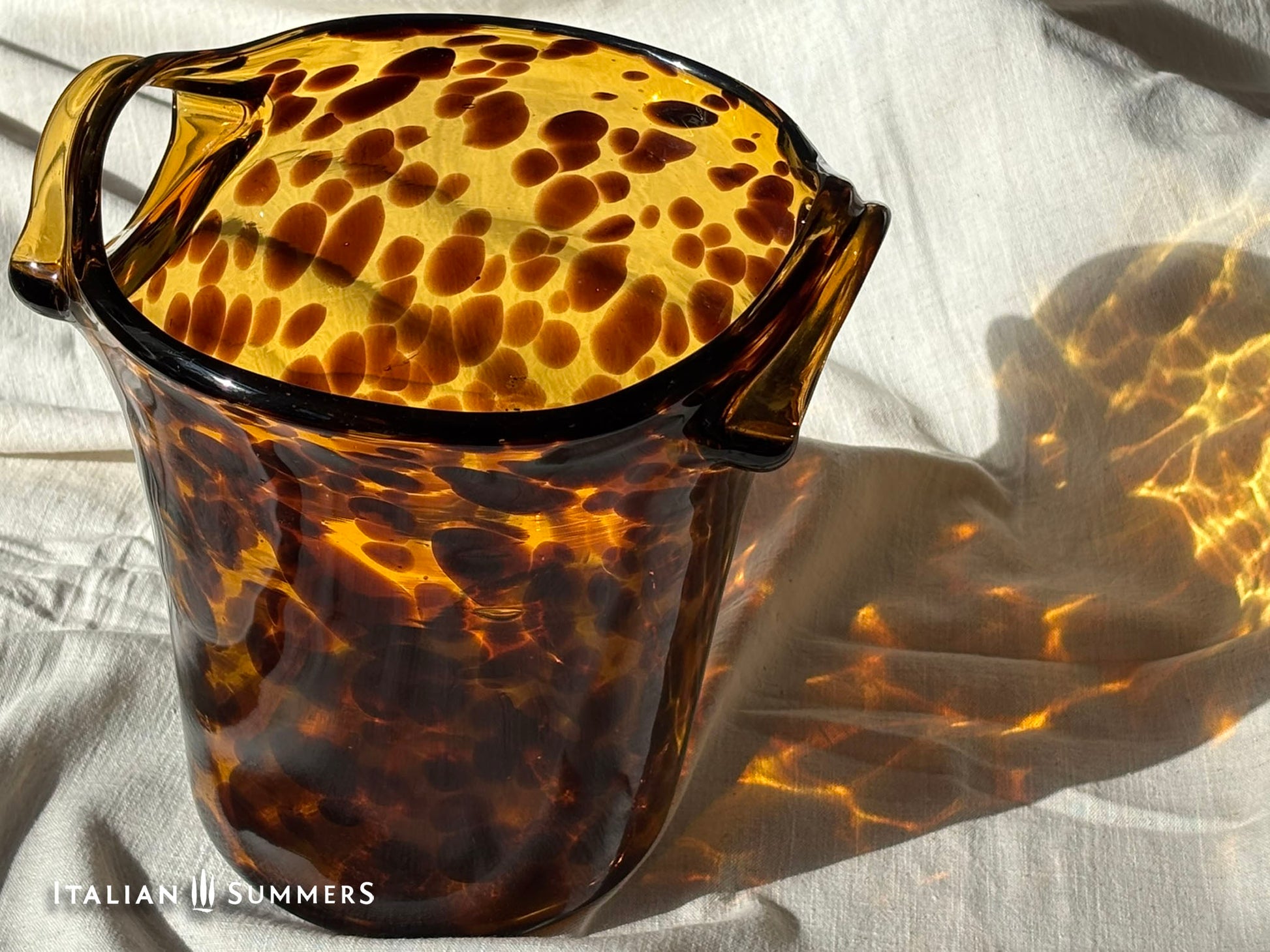 Tortoiseshell patterned glass ice bucket on a light fabric background