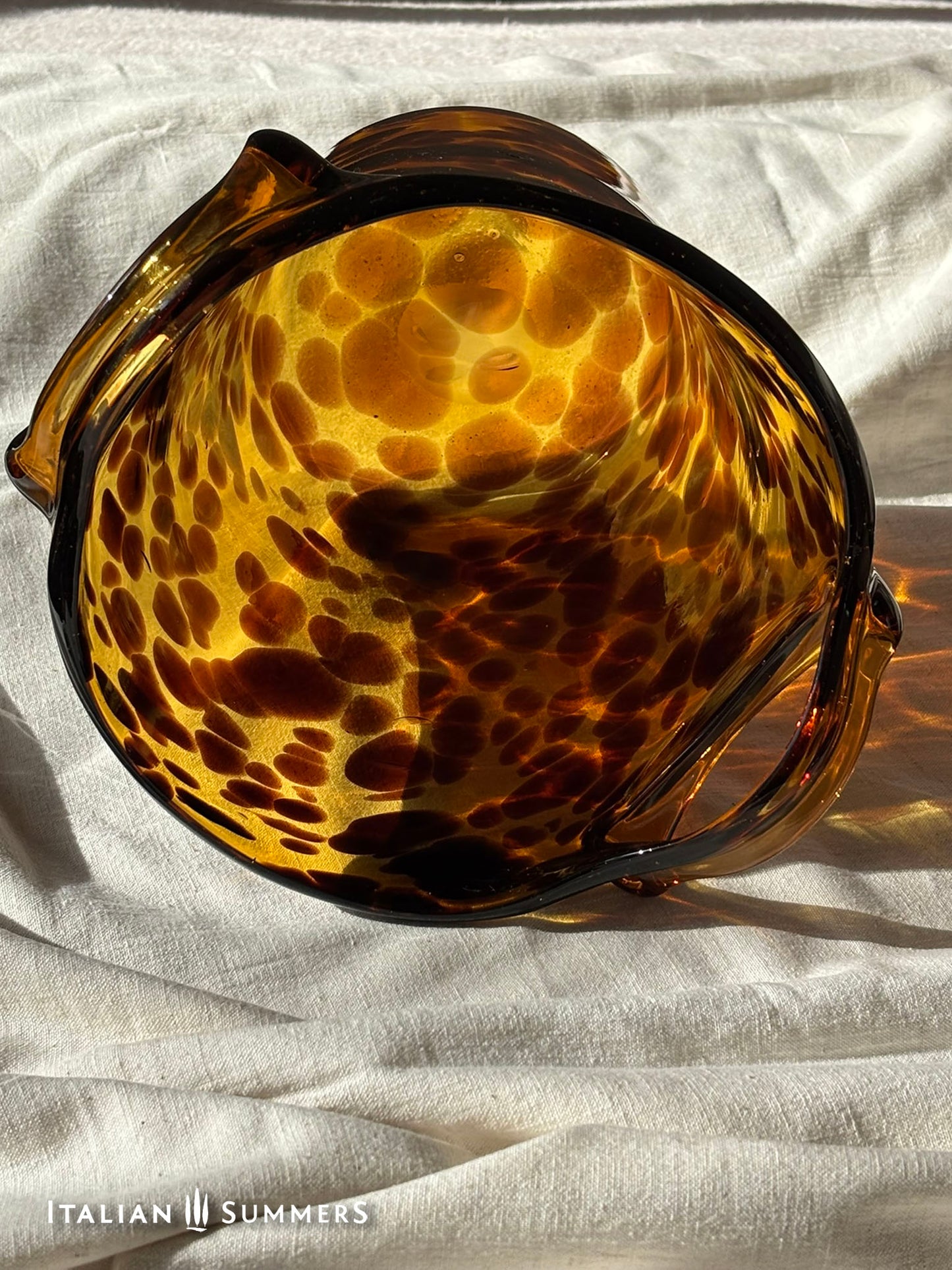 Tortoiseshell patterned glass ice bucket on a light fabric background