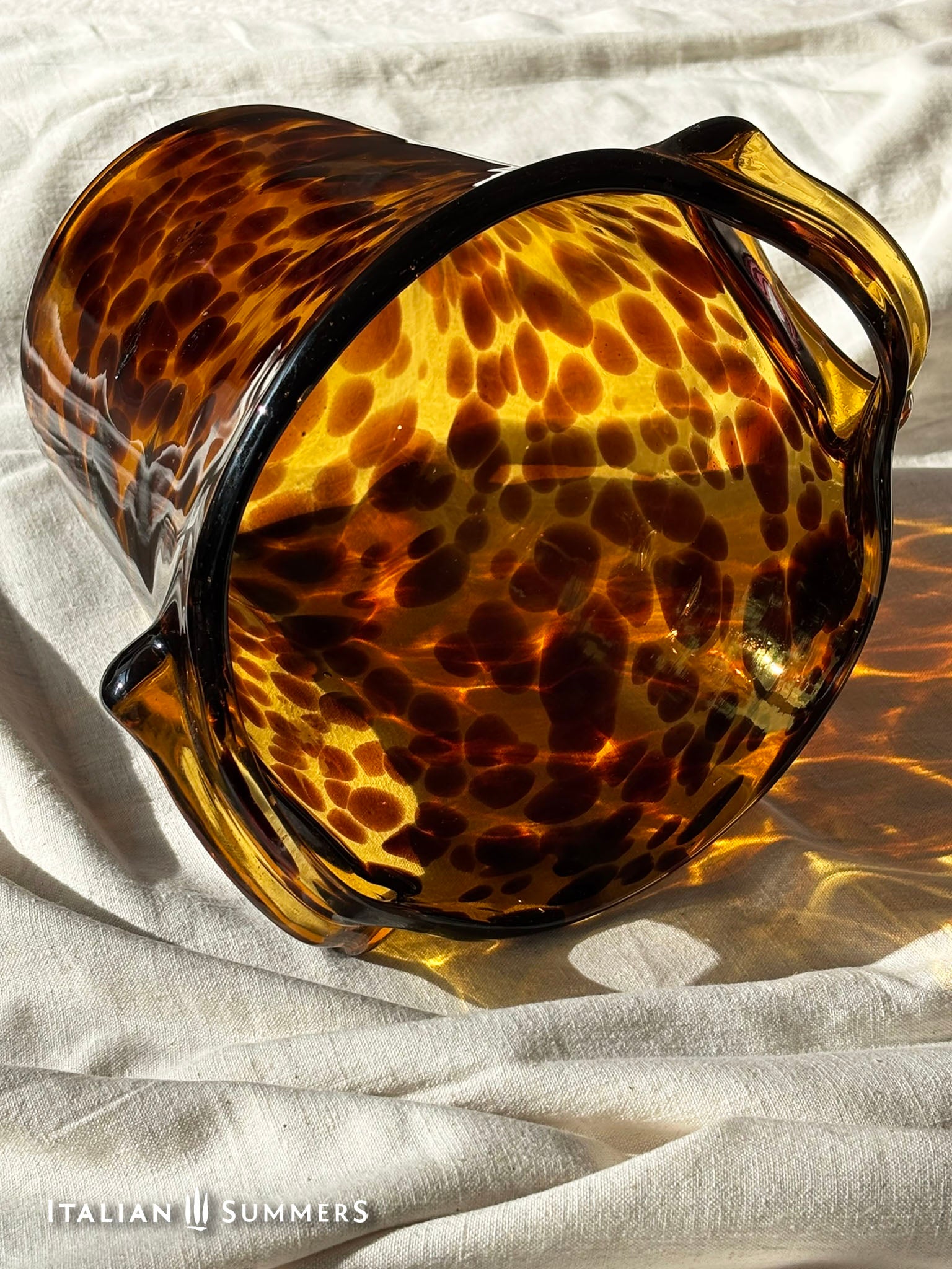 Tortoiseshell patterned glass champagne chiller bucket 
on a textured white surface with 'Italian Summers' branding.