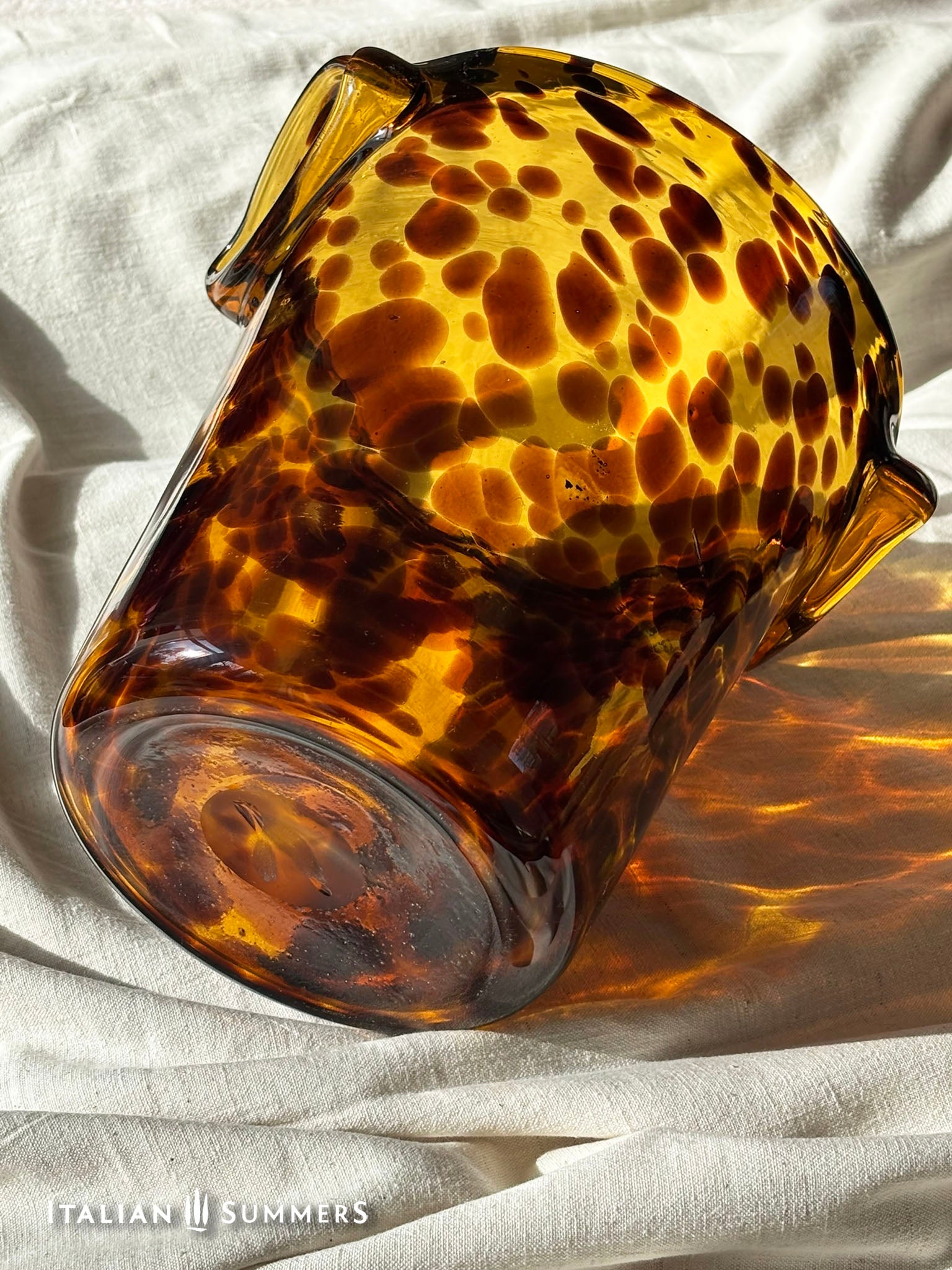 Tortoiseshell patterned glass ice bucket on a light fabric background