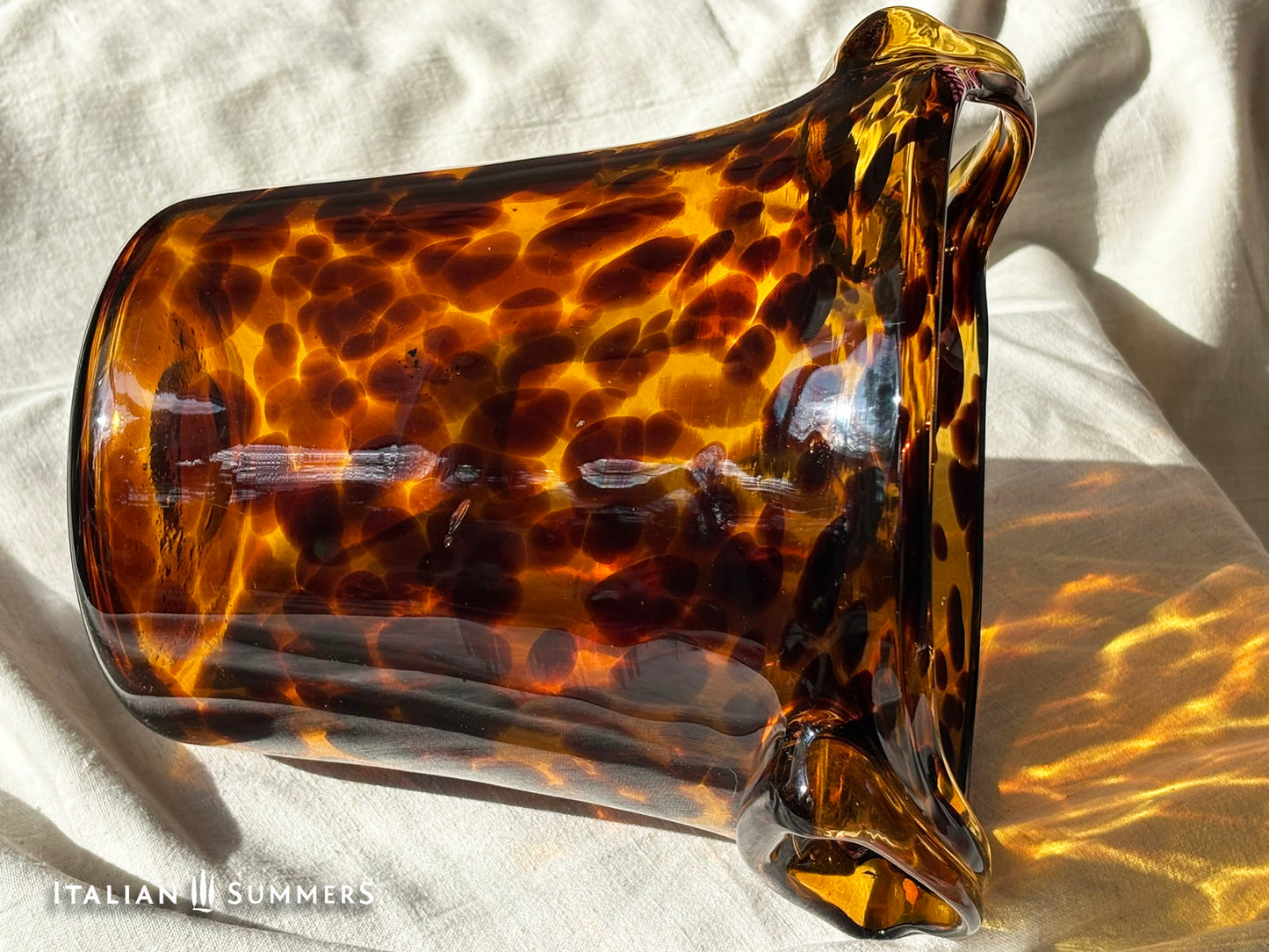 Tortoiseshell patterned glass ice bucket on a light fabric background
