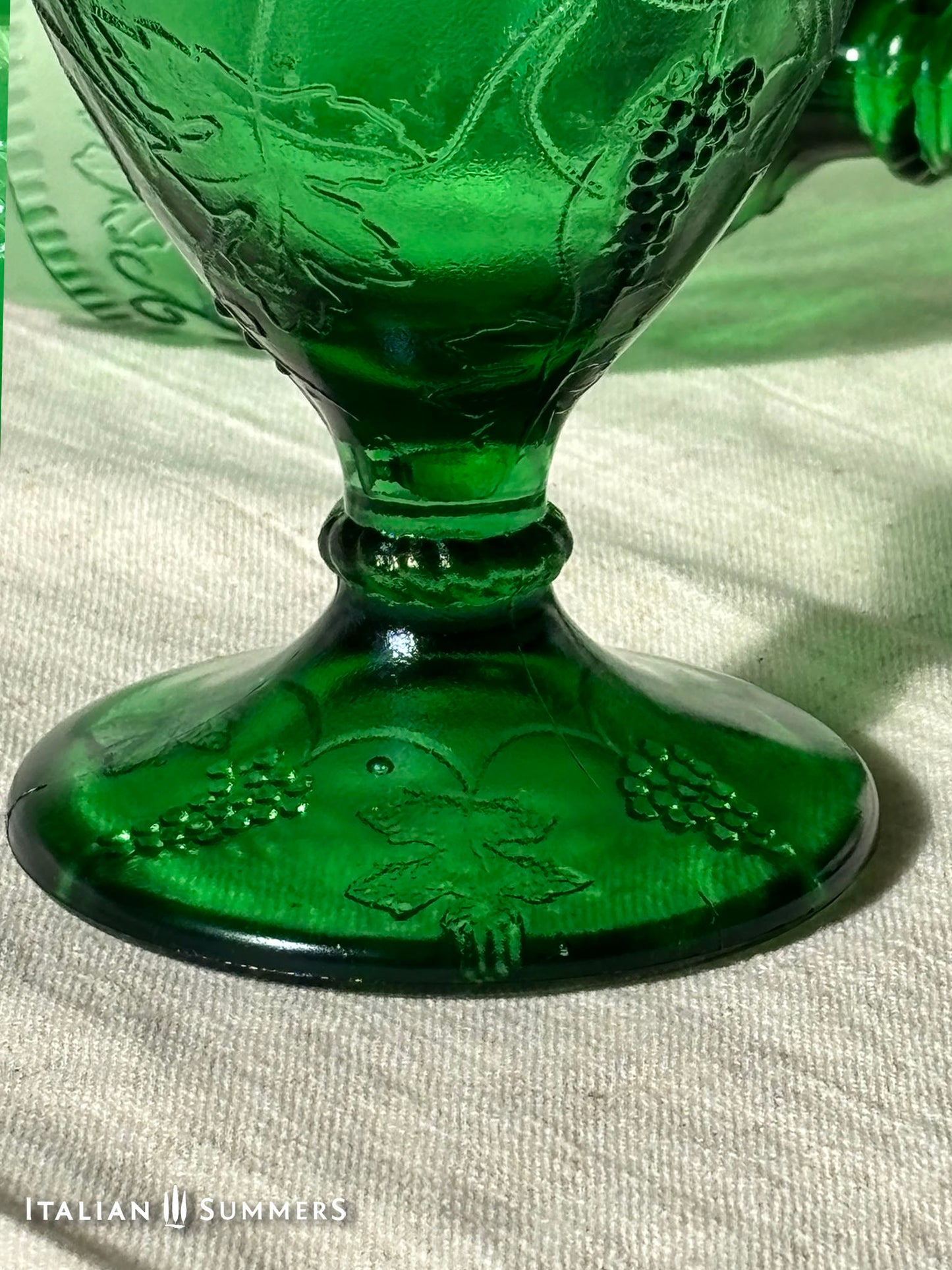 Green glass goblet with embossed design on a white background