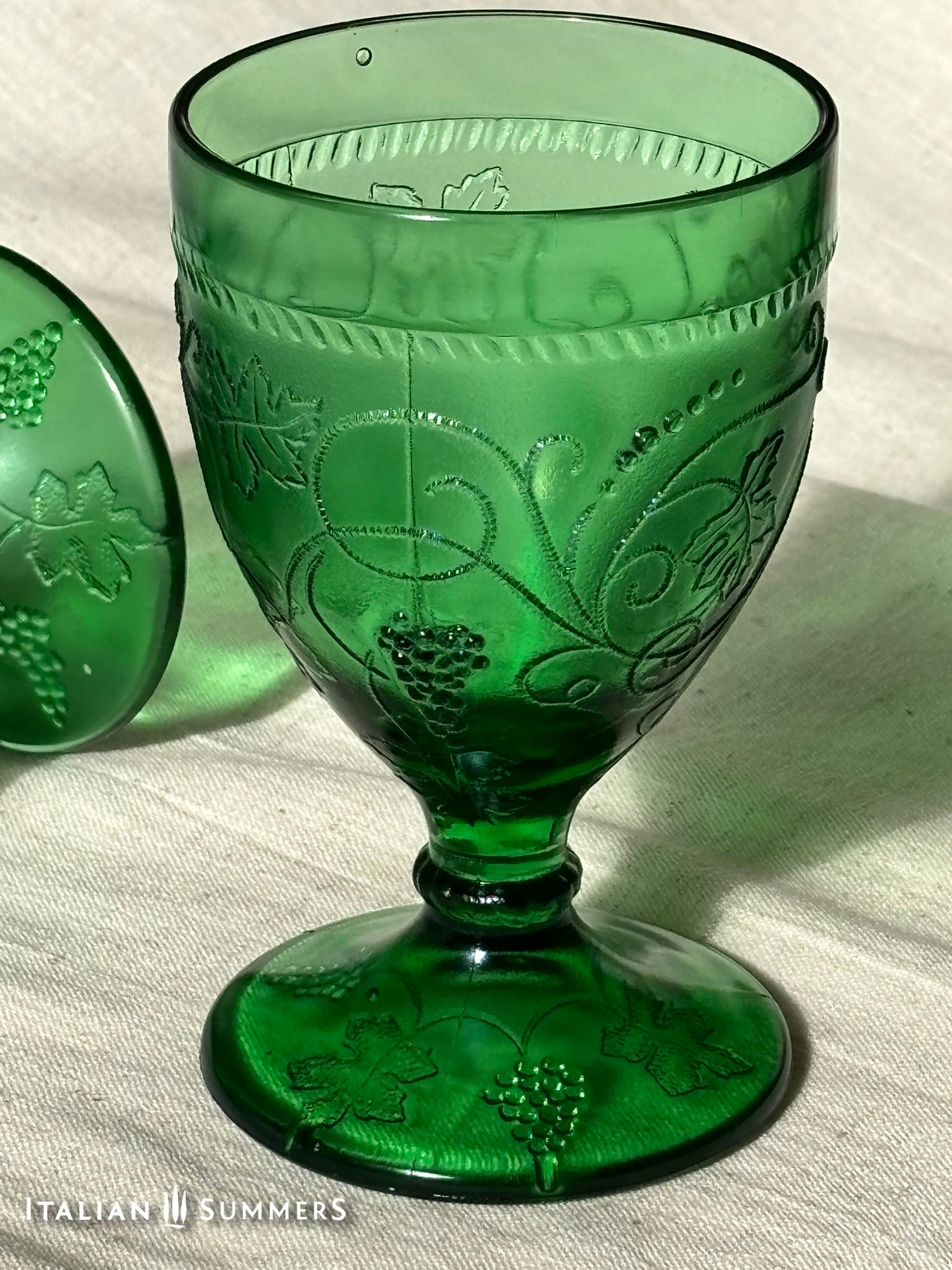 Green glass goblet with embossed design on a light background